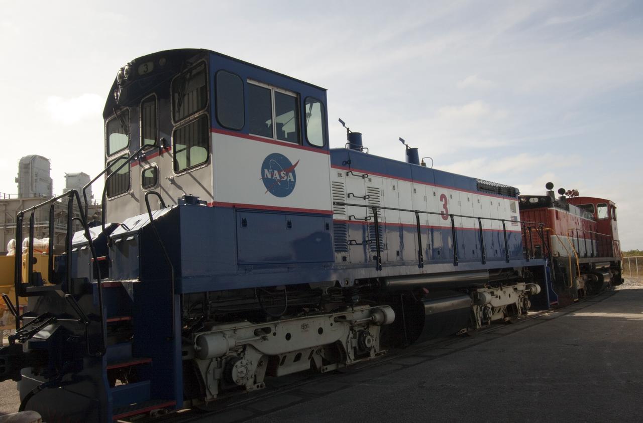 CAPE CANAVERAL, Fla. – NASA locomotive No. 1 pulls locomotive No. 3 out of the Rotation, Processing and Surge Facility, or RPSF, at the Kennedy Space Center in Florida. Inside, an overhead crane was used to lift NASA locomotive No. 2 off of its trucks and moved aside, so locomotive No. 3 could be raised off its trucks and moved into position atop the trucks previously used by locomotive No. 2.      The RPSF was built to support work on the solid rocket used motors during the space shuttle era. The facility had never previously been used for another purpose, but is now free to serve other customers. With rails running into the building's high bay and a pair of heavy-lift cranes positioned overhead, the facility's capabilities were a perfect fit for the NASA Railroad's needs. Railroad managers wanted to trade the wheel and axle assemblies, or trucks, of locomotives No. 2 and No. 3. Locomotive No. 3 was painstakingly restored in recent years by the NASA Railroad team, and handles much of the rail work required at the center in the post-shuttle era. But the trucks on locomotive No. 2 are in better shape and are more environmentally friendly. For more information, visit: http://www.nasa.gov/exploration/systems/ground/rpsf_locomotives.html Photo credit: NASA/Jim Grossmann