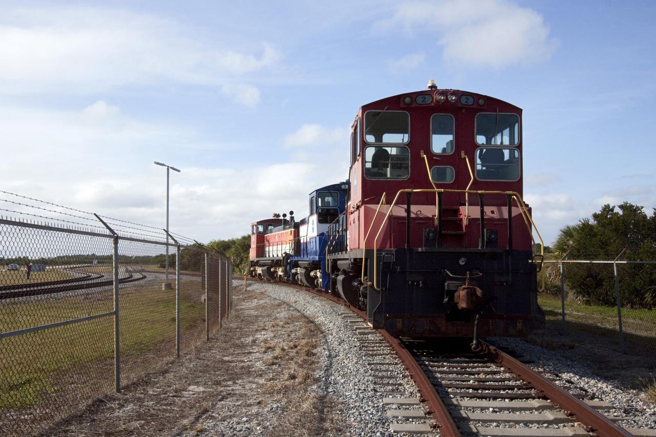CAPE CANAVERAL, Fla. – At Kennedy Space Center in Florida, NASA railroad locomotive No. 1 pulls locomotives 2 and 3 away from Launch Complex 39 area's Rotation, Processing and Surge Facility, or RPSF, where wheel and axle assemblies were swapped between locomotives 2 and 3.      The RPSF was built to support work on the solid rocket used motors during the space shuttle era. The facility had never previously been used for another purpose, but is now free to serve other customers. With rails running into the building's high bay and a pair of heavy-lift cranes positioned overhead, the facility's capabilities were a perfect fit for the NASA Railroad's needs. Railroad managers wanted to trade the wheel and axle assemblies, or trucks, of locomotives No. 2 and No. 3. Locomotive No. 3 was painstakingly restored in recent years by the NASA Railroad team, and handles much of the rail work required at the center in the post-shuttle era. But the trucks on locomotive No. 2 are in better shape and are more environmentally friendly. For more information, visit: http://www.nasa.gov/exploration/systems/ground/rpsf_locomotives.html Photo credit: NASA/Jim Grossmann