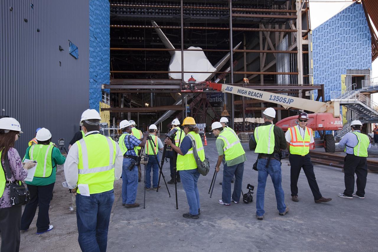 CAPE CANAVERAL, Fla. – Members of the media get an up close view of space shuttle Atlantis in her new home at the Kennedy Space Center Visitor Complex in Florida. The shuttle is wrapped in a protective plastic to protect it from dust and debris while being prepared for display. Atlantis was lifted 26 feet from the ground level and slowly tilted to exactly a 43.21 angle to its portside to allow optimum viewing of the vehicle with its payload bay doors open. Atlantis is being prepared for display in the new 90,000-square-foot facility under construction at the visitor complex which is managed by Delaware North Companies Parks & Resorts. Photo credit: NASA/Dimitri Gerondidakis