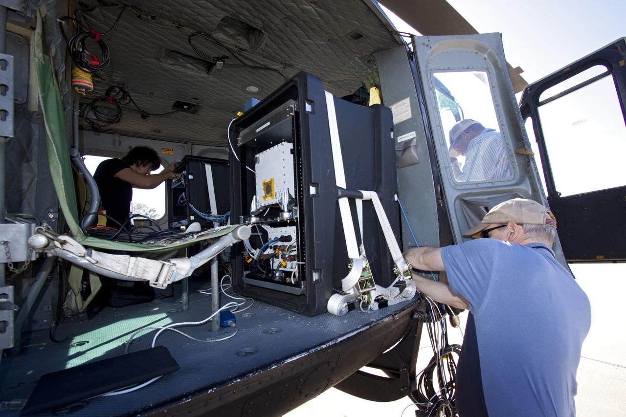 CAPE CANAVERAL, Fla. – Near the Shuttle Landing Facility at NASA's Kennedy Space Center in Florida, a technician installs hazard avoidance instrumentation on a Huey helicopter. Led by the Johnson Space Center and supported by Jet Propulsion Laboratory and Langley Research Center, the Autonomous Landing Hazard Avoidance Technology, or ALHAT, laser system provides a planetary lander the ability to precisely land safely on a surface while detecting any dangerous obstacles such as rocks, holes and slopes. Just north of Kennedy's Shuttle Landing Facility runway, a rock- and crater-filled planetary scape has been built so engineers can test the ability to negotiate away from risks. Photo credit: NASA/Jim Grossmann
