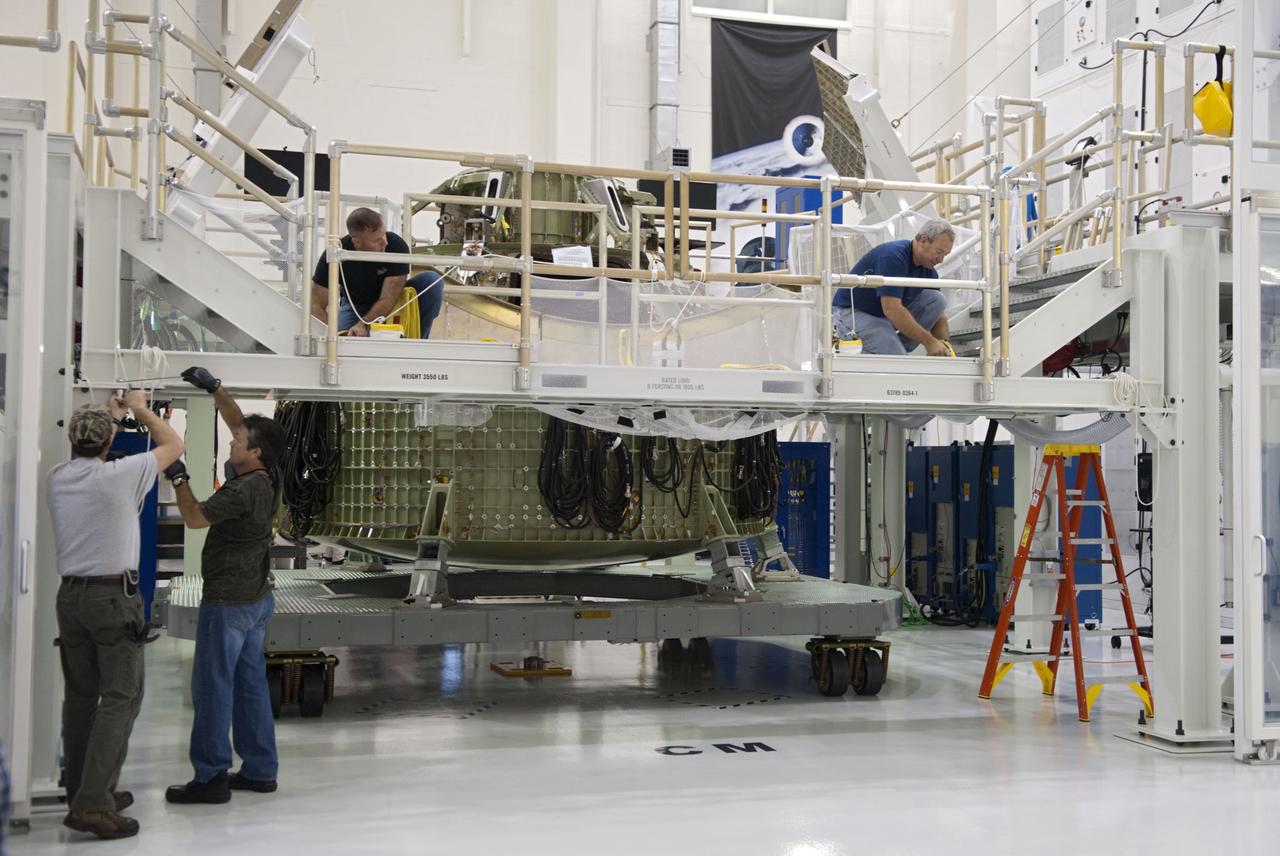 CAPE CANAVERAL, Fla. – Technicians prepare to fit a special fixture around an Orion capsule inside the high bay of the Operations & Checkout Building at NASA's Kennedy Space Center in Florida. The fixture is designed to enable precise pre-launch processing of the Orion spacecraft. An Orion capsule is being prepared to make a flight test in 2014 on a mission that will not carry any astronauts. Photo by Tim Jacobs