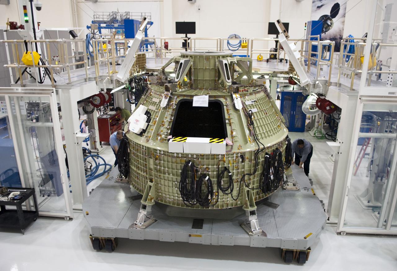 CAPE CANAVERAL, Fla. – Technicians prepare to fit a special fixture around an Orion capsule inside the high bay of the Operations & Checkout Building at NASA's Kennedy Space Center in Florida. The fixture is designed to enable precise pre-launch processing of the Orion spacecraft. An Orion capsule is being prepared to make a flight test in 2014 on a mission that will not carry any astronauts. Photo by Tim Jacobs