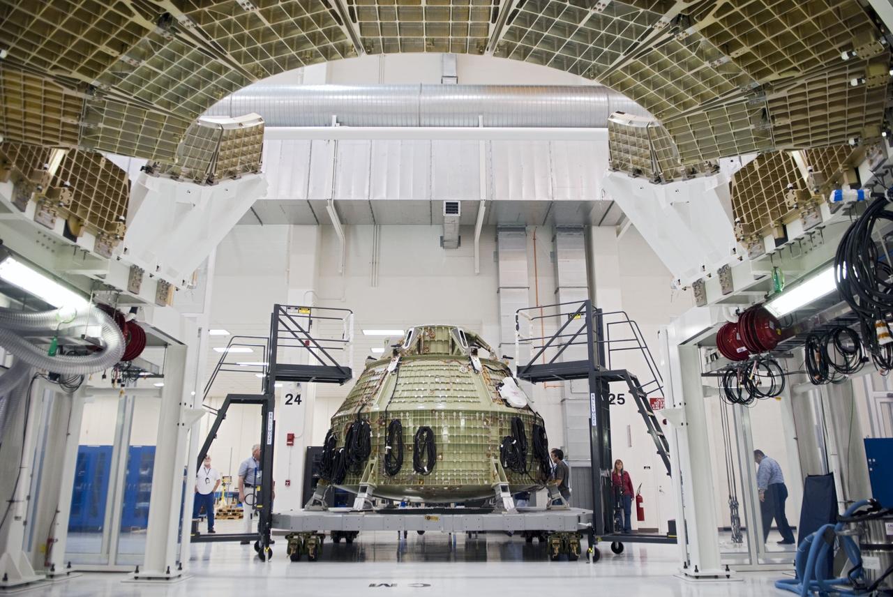 CAPE CANAVERAL, Fla. – Technicians prepare to fit a special fixture around an Orion capsule inside the high bay of the Operations & Checkout Building at NASA's Kennedy Space Center in Florida. The fixture is designed to enable precise pre-launch processing of the Orion spacecraft. An Orion capsule is being prepared to make a flight test in 2014 on a mission that will not carry any astronauts. Photo by Tim Jacobs