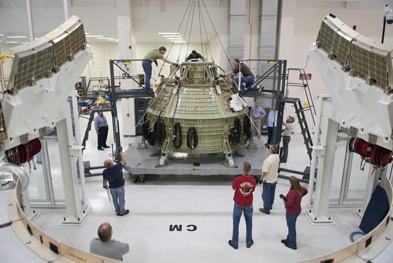 CAPE CANAVERAL, Fla. – Technicians prepare to fit a special fixture around an Orion capsule inside the high bay of the Operations & Checkout Building at NASA's Kennedy Space Center in Florida. The fixture is designed to enable precise pre-launch processing of the Orion spacecraft. An Orion capsule is being prepared to make a flight test in 2014 on a mission that will not carry any astronauts. Photo by Tim Jacobs