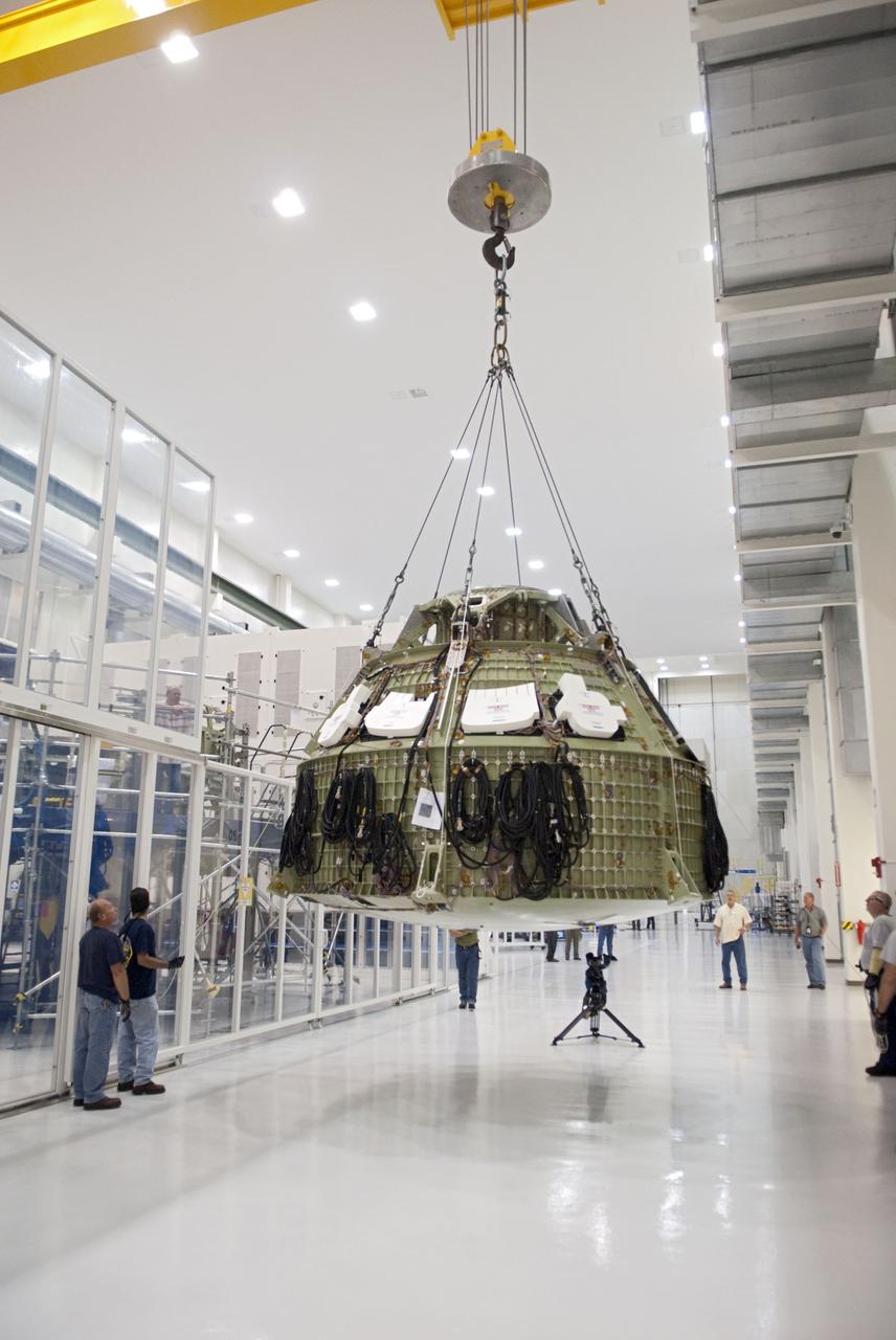 CAPE CANAVERAL, Fla. – Technicians prepare to fit a special fixture around an Orion capsule inside the high bay of the Operations & Checkout Building at NASA's Kennedy Space Center in Florida. The fixture is designed to enable precise pre-launch processing of the Orion spacecraft. An Orion capsule is being prepared to make a flight test in 2014 on a mission that will not carry any astronauts. Photo by Tim Jacobs