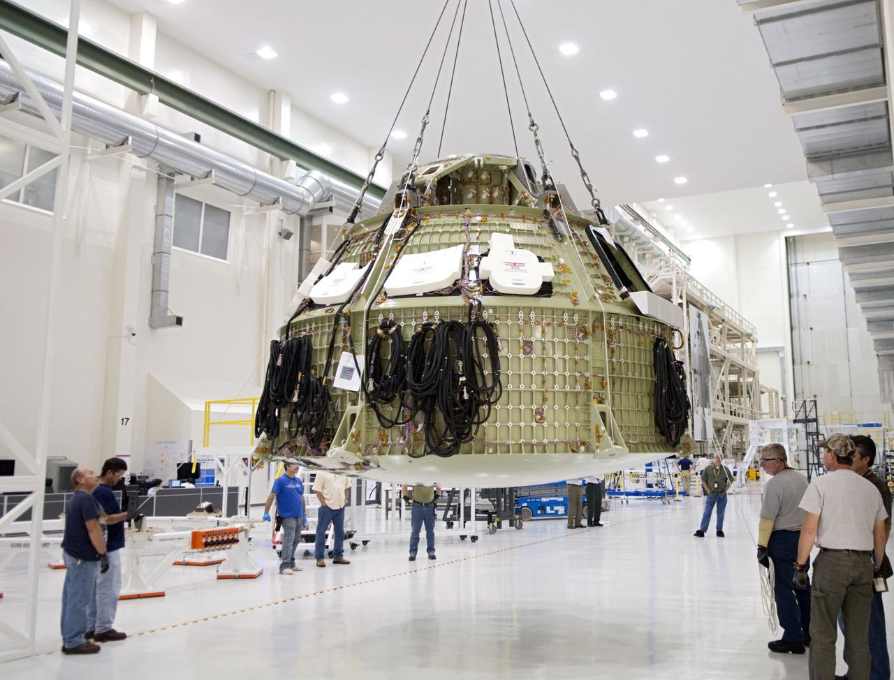 CAPE CANAVERAL, Fla. – Technicians prepare to fit a special fixture around an Orion capsule inside the high bay of the Operations & Checkout Building at NASA's Kennedy Space Center in Florida. The fixture is designed to enable precise pre-launch processing of the Orion spacecraft. An Orion capsule is being prepared to make a flight test in 2014 on a mission that will not carry any astronauts. Photo by Tim Jacobs