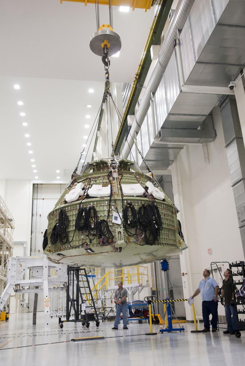 CAPE CANAVERAL, Fla. – Technicians prepare to fit a special fixture around an Orion capsule inside the high bay of the Operations & Checkout Building at NASA's Kennedy Space Center in Florida. The fixture is designed to enable precise pre-launch processing of the Orion spacecraft. An Orion capsule is being prepared to make a flight test in 2014 on a mission that will not carry any astronauts. Photo by Tim Jacobs