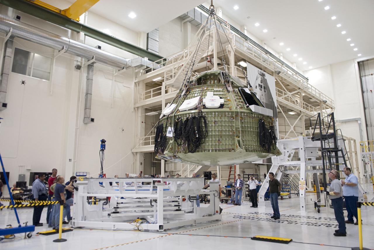 CAPE CANAVERAL, Fla. – Technicians prepare to fit a special fixture around an Orion capsule inside the high bay of the Operations & Checkout Building at NASA's Kennedy Space Center in Florida. The fixture is designed to enable precise pre-launch processing of the Orion spacecraft. An Orion capsule is being prepared to make a flight test in 2014 on a mission that will not carry any astronauts. Photo by Tim Jacobs