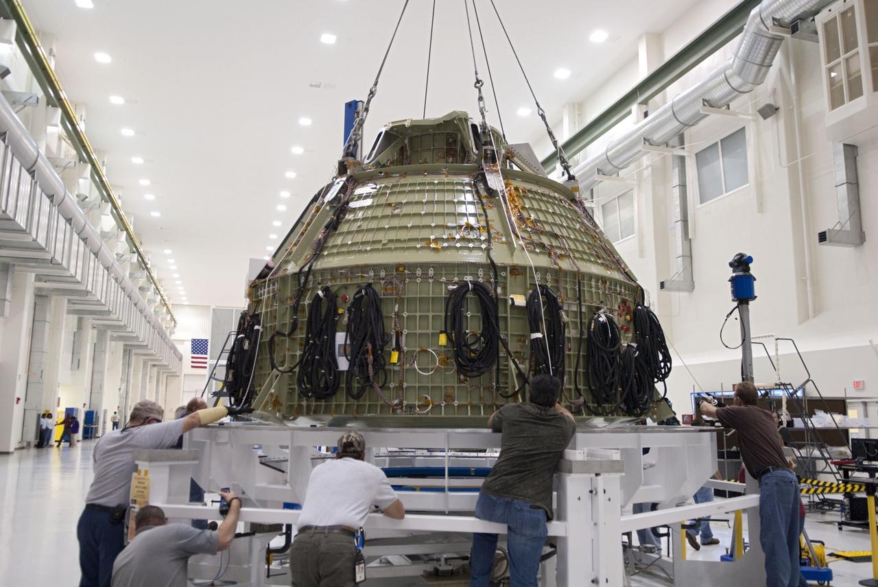 CAPE CANAVERAL, Fla. – Technicians prepare to fit a special fixture around an Orion capsule inside the high bay of the Operations & Checkout Building at NASA's Kennedy Space Center in Florida. The fixture is designed to enable precise pre-launch processing of the Orion spacecraft. An Orion capsule is being prepared to make a flight test in 2014 on a mission that will not carry any astronauts. Photo by Tim Jacobs