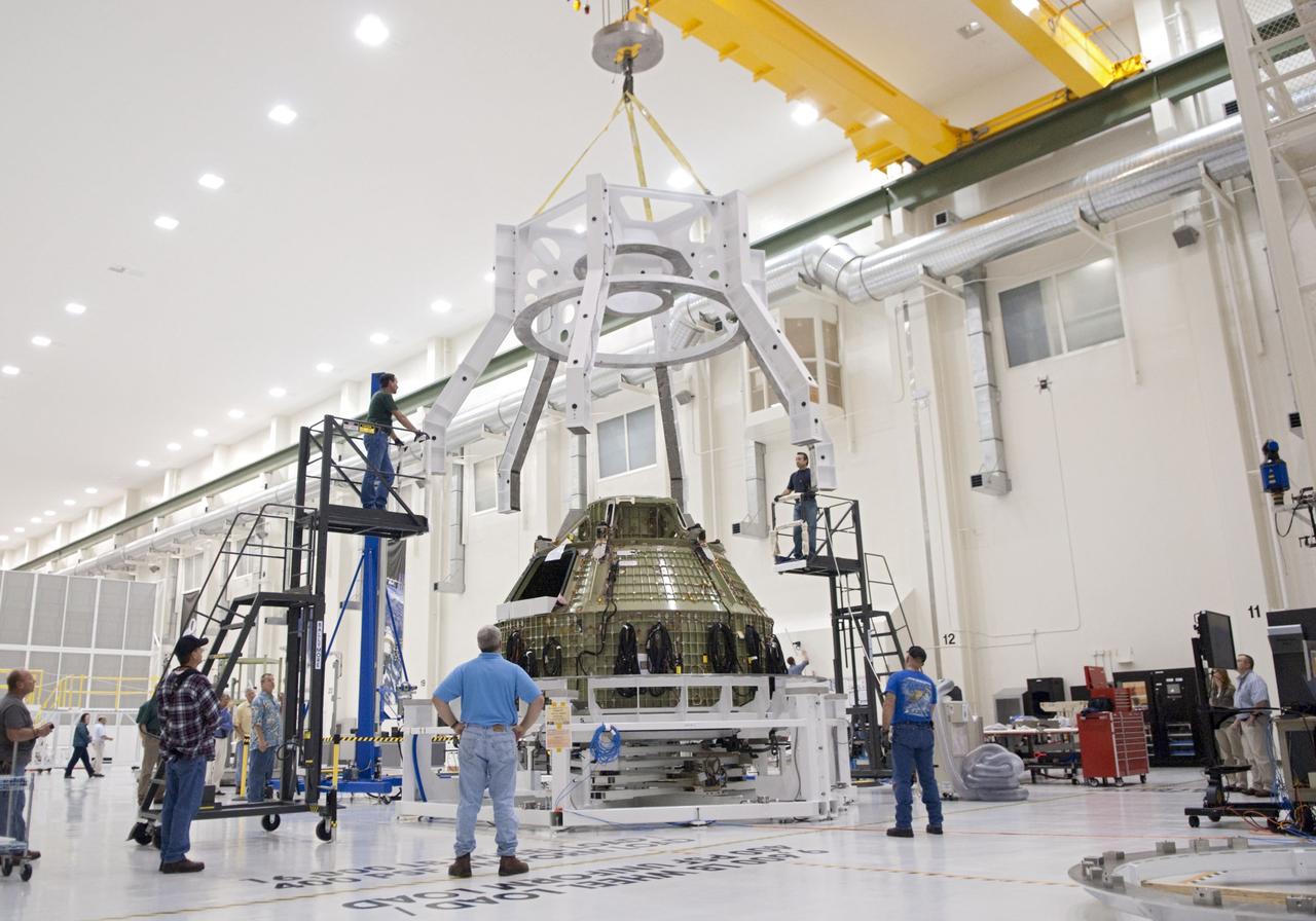 CAPE CANAVERAL, Fla. – Technicians lift a special fixture inside the high bay of the Operations & Checkout Building at NASA's Kennedy Space Center in Florida. The fixture is designed to enable precise pre-launch processing of the Orion spacecraft. An Orion capsule is being prepared to make a flight test in 2014 on a mission that will not carry any astronauts. Photo by Tim Jacobs