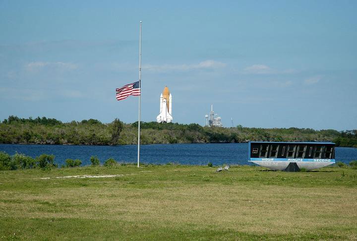 View of Space Shuttle Discovery, framed by Flag Pole and Clock, on its way to LC39B for the second Return to Flight, April 6, 2005. (The flag is at half-mast in remembrance of Pope John Paul II.)