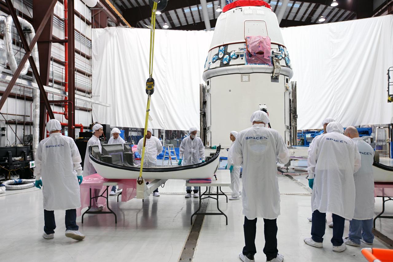CAPE CANAVERAL, Fla. – Workers prepare to lift a solar array fairing at the processing hangar used by Space Exploration Technologies, or SpaceX, at Cape Canaveral Air Force Station, Fla. The fairing will be installed on the Dragon spacecraft undergoing launch preparations inside the hangar. The spacecraft will launch on the upcoming SpaceX CRS-2 mission. The flight will be the second commercial resupply mission to the International Space Station by SpaceX. NASA has contracted for a total of 12 commercial resupply flights from SpaceX and eight from the Orbital Sciences Corp. Photo credit: NASA/Kim Shiflett
