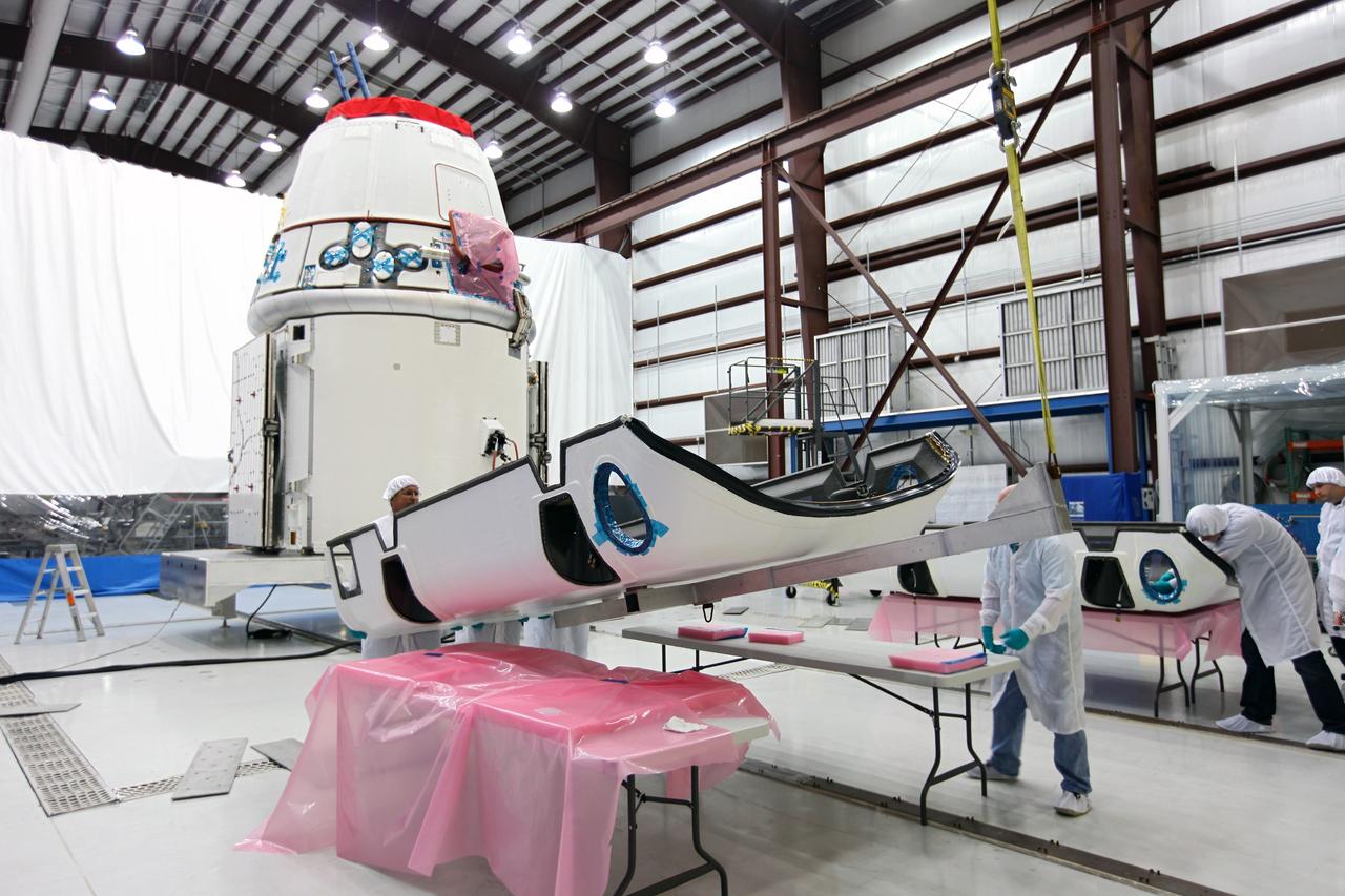 CAPE CANAVERAL, Fla. – Workers lift a solar array fairing at the processing hangar used by Space Exploration Technologies, or SpaceX, at Cape Canaveral Air Force Station, Fla. The fairing will be installed on the Dragon spacecraft undergoing launch preparations inside the hangar. The spacecraft will launch on the upcoming SpaceX CRS-2 mission. The flight will be the second commercial resupply mission to the International Space Station by SpaceX. NASA has contracted for a total of 12 commercial resupply flights from SpaceX and eight from the Orbital Sciences Corp. Photo credit: NASA/Kim Shiflett