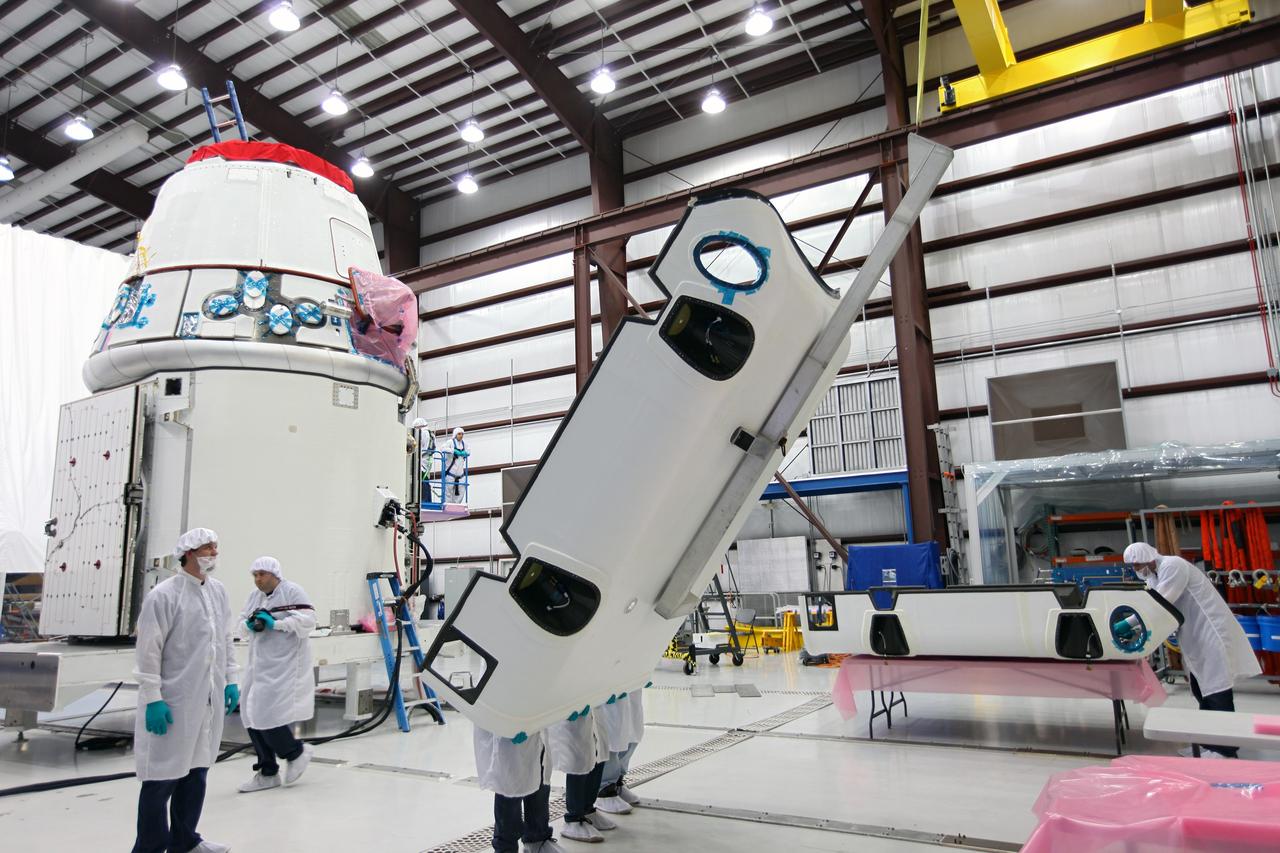 CAPE CANAVERAL, Fla. – Workers lift a solar array fairing at the processing hangar used by Space Exploration Technologies, or SpaceX, at Cape Canaveral Air Force Station, Fla. The fairing will be installed on the Dragon spacecraft undergoing launch preparations inside the hangar. The spacecraft will launch on the upcoming SpaceX CRS-2 mission. The flight will be the second commercial resupply mission to the International Space Station by SpaceX. NASA has contracted for a total of 12 commercial resupply flights from SpaceX and eight from the Orbital Sciences Corp. Photo credit: NASA/Kim Shiflett