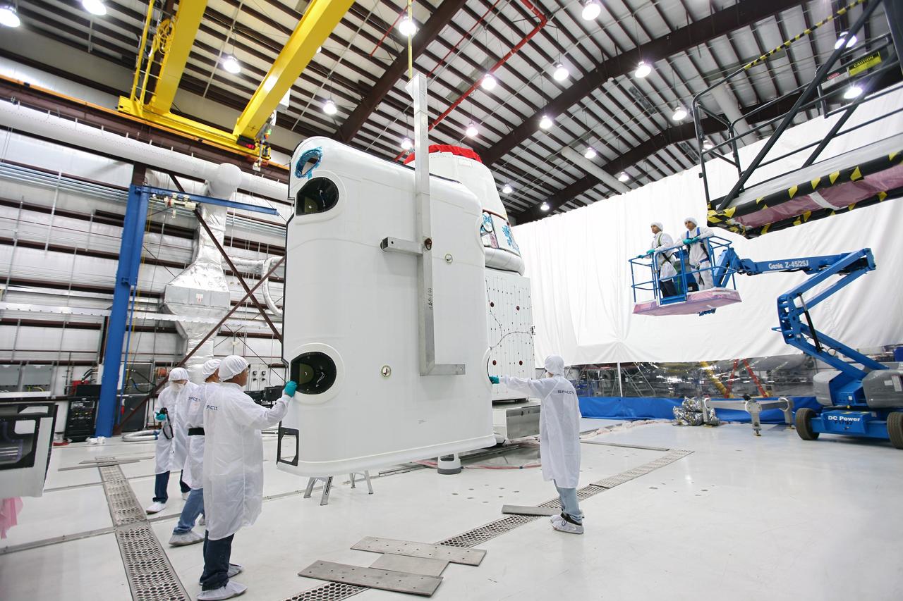 CAPE CANAVERAL, Fla. – Workers guide a solar array fairing into place inside the processing hangar used by Space Exploration Technologies, or SpaceX, at Cape Canaveral Air Force Station, Fla. The fairing will be installed on the Dragon spacecraft undergoing launch preparations inside the hangar. The spacecraft will launch on the upcoming SpaceX CRS-2 mission. The flight will be the second commercial resupply mission to the International Space Station by SpaceX. NASA has contracted for a total of 12 commercial resupply flights from SpaceX and eight from the Orbital Sciences Corp. Photo credit: NASA/Kim Shiflett