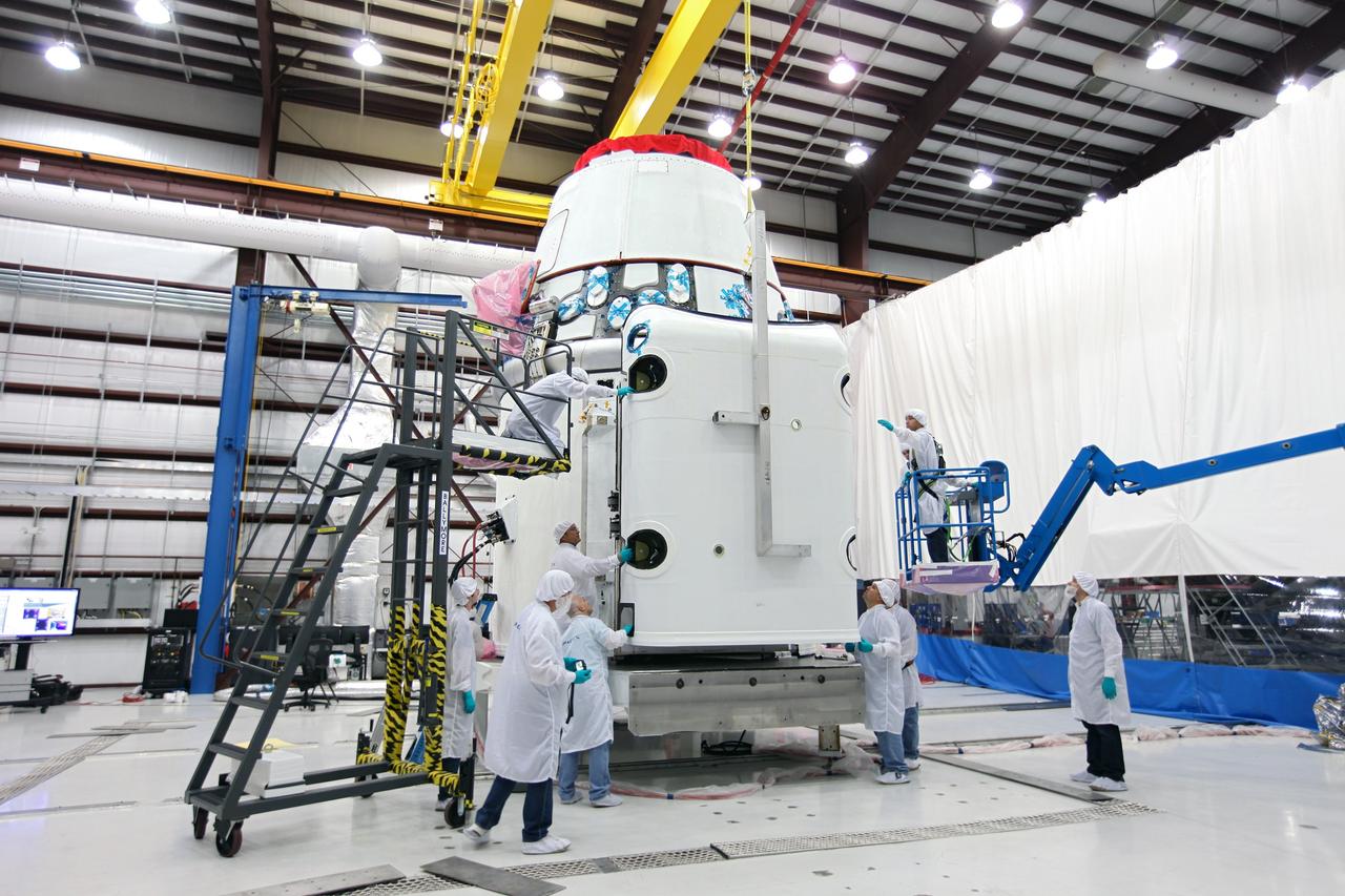 CAPE CANAVERAL, Fla. – Workers guide a solar array fairing into place inside the processing hangar used by Space Exploration Technologies, or SpaceX, at Cape Canaveral Air Force Station, Fla. The fairing will be installed on the Dragon spacecraft undergoing launch preparations inside the hangar. The spacecraft will launch on the upcoming SpaceX CRS-2 mission. The flight will be the second commercial resupply mission to the International Space Station by SpaceX. NASA has contracted for a total of 12 commercial resupply flights from SpaceX and eight from the Orbital Sciences Corp. Photo credit: NASA/Kim Shiflett