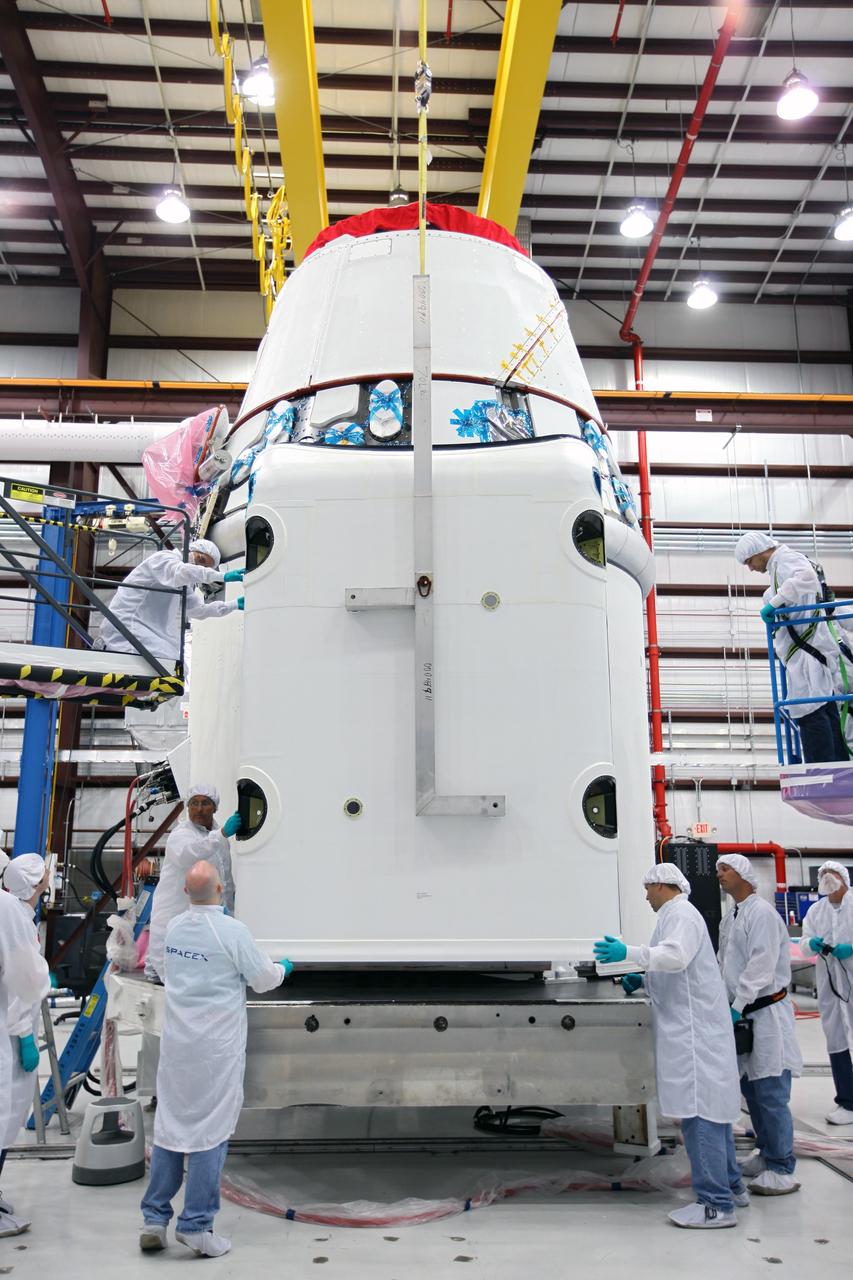 CAPE CANAVERAL, Fla. – Workers guide a solar array fairing into place inside the processing hangar used by Space Exploration Technologies, or SpaceX, at Cape Canaveral Air Force Station, Fla. The fairing will be installed on the Dragon spacecraft undergoing launch preparations inside the hangar. The spacecraft will launch on the upcoming SpaceX CRS-2 mission. The flight will be the second commercial resupply mission to the International Space Station by SpaceX. NASA has contracted for a total of 12 commercial resupply flights from SpaceX and eight from the Orbital Sciences Corp. Photo credit: NASA/Kim Shiflett