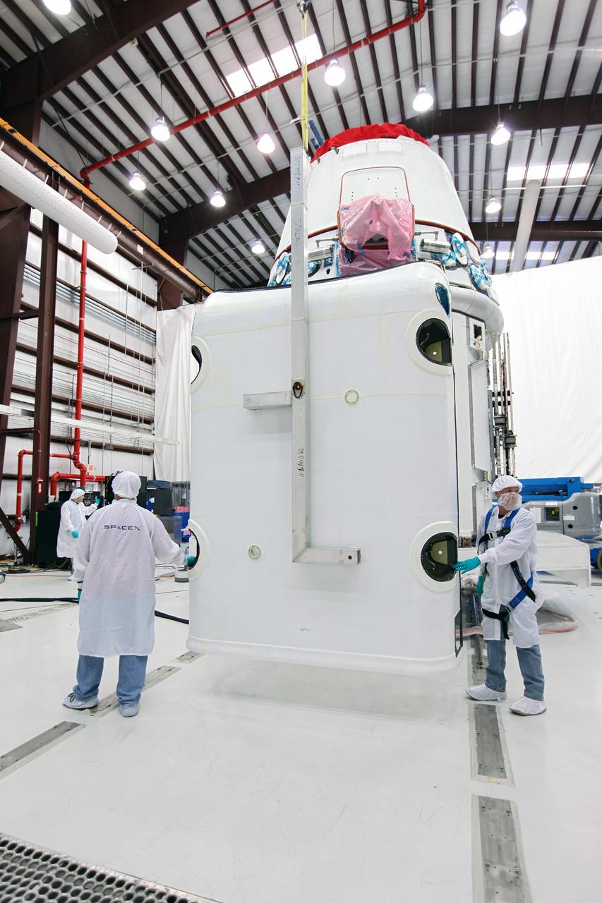 CAPE CANAVERAL, Fla. – Workers guide a solar array fairing into place inside the processing hangar used by Space Exploration Technologies, or SpaceX, at Cape Canaveral Air Force Station, Fla. The fairing will be installed on the Dragon spacecraft undergoing launch preparations inside the hangar. The spacecraft will launch on the upcoming SpaceX CRS-2 mission. The flight will be the second commercial resupply mission to the International Space Station by SpaceX. NASA has contracted for a total of 12 commercial resupply flights from SpaceX and eight from the Orbital Sciences Corp. Photo credit: NASA/Kim Shiflett