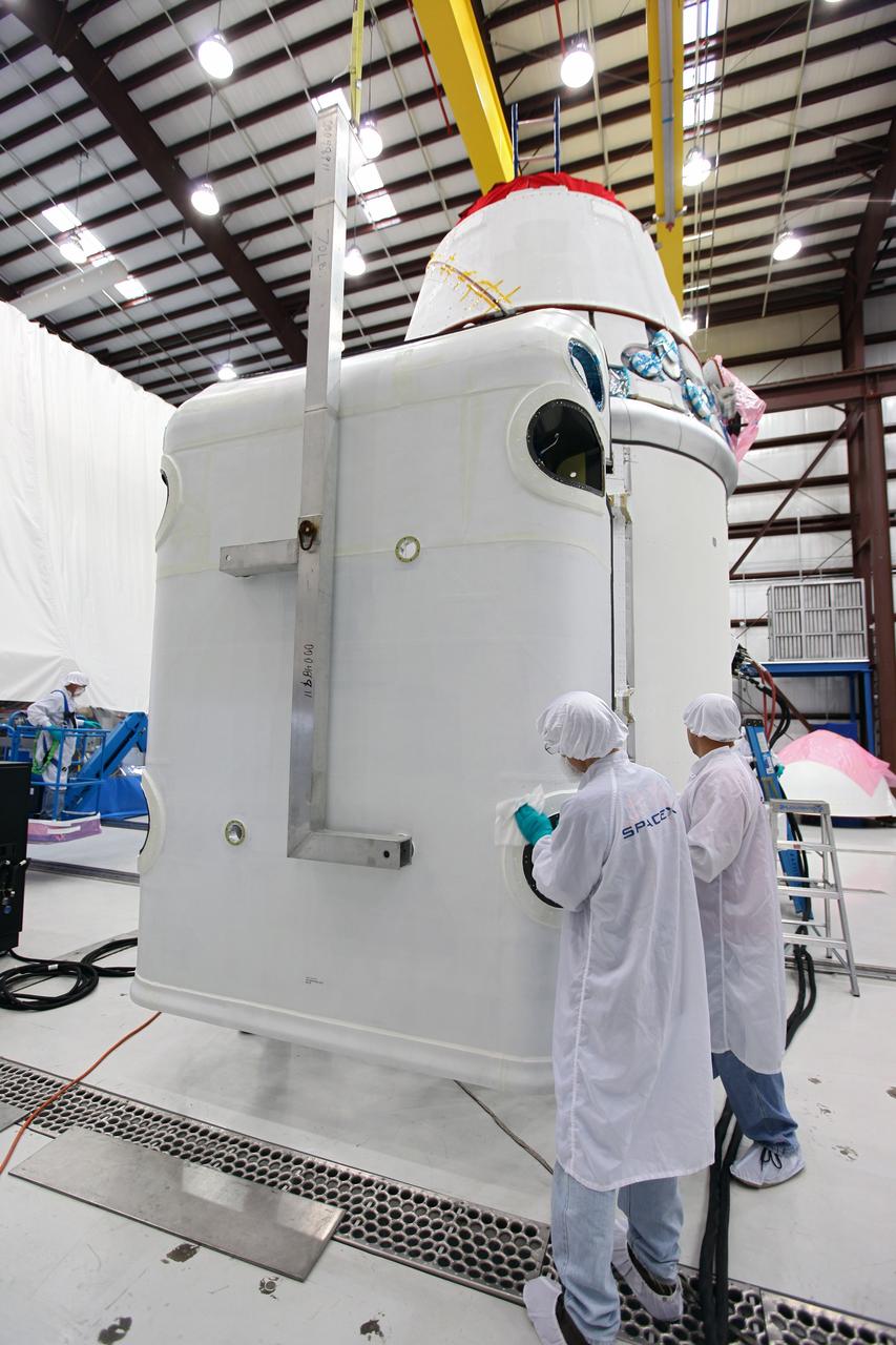 CAPE CANAVERAL, Fla. – Workers guide a solar array fairing into place inside the processing hangar used by Space Exploration Technologies, or SpaceX, at Cape Canaveral Air Force Station, Fla. The fairing will be installed on the Dragon spacecraft undergoing launch preparations inside the hangar. The spacecraft will launch on the upcoming SpaceX CRS-2 mission. The flight will be the second commercial resupply mission to the International Space Station by SpaceX. NASA has contracted for a total of 12 commercial resupply flights from SpaceX and eight from the Orbital Sciences Corp. Photo credit: NASA/Kim Shiflett