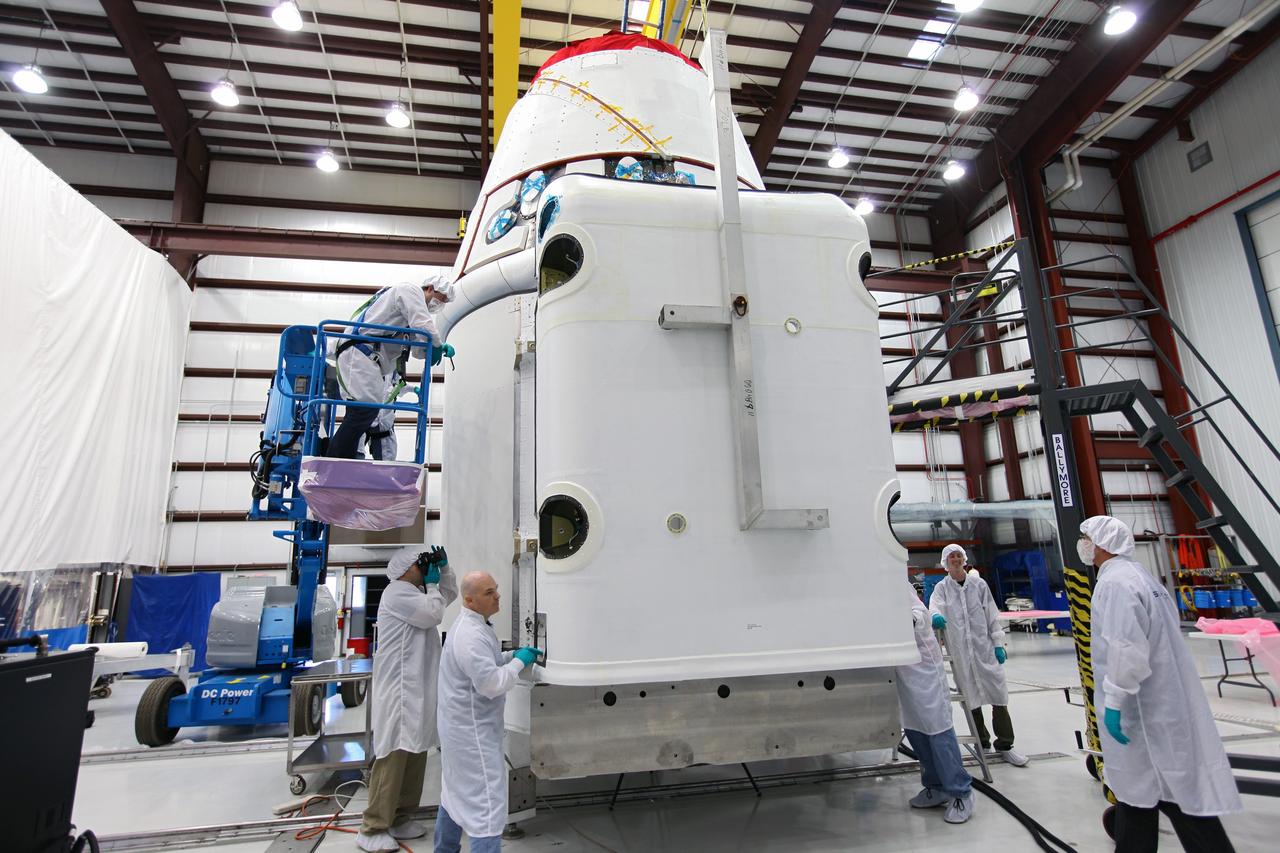 CAPE CANAVERAL, Fla. – Workers guide a solar array fairing into place inside the processing hangar used by Space Exploration Technologies, or SpaceX, at Cape Canaveral Air Force Station, Fla. The fairing will be installed on the Dragon spacecraft undergoing launch preparations inside the hangar. The spacecraft will launch on the upcoming SpaceX CRS-2 mission. The flight will be the second commercial resupply mission to the International Space Station by SpaceX. NASA has contracted for a total of 12 commercial resupply flights from SpaceX and eight from the Orbital Sciences Corp. Photo credit: NASA/Kim Shiflett