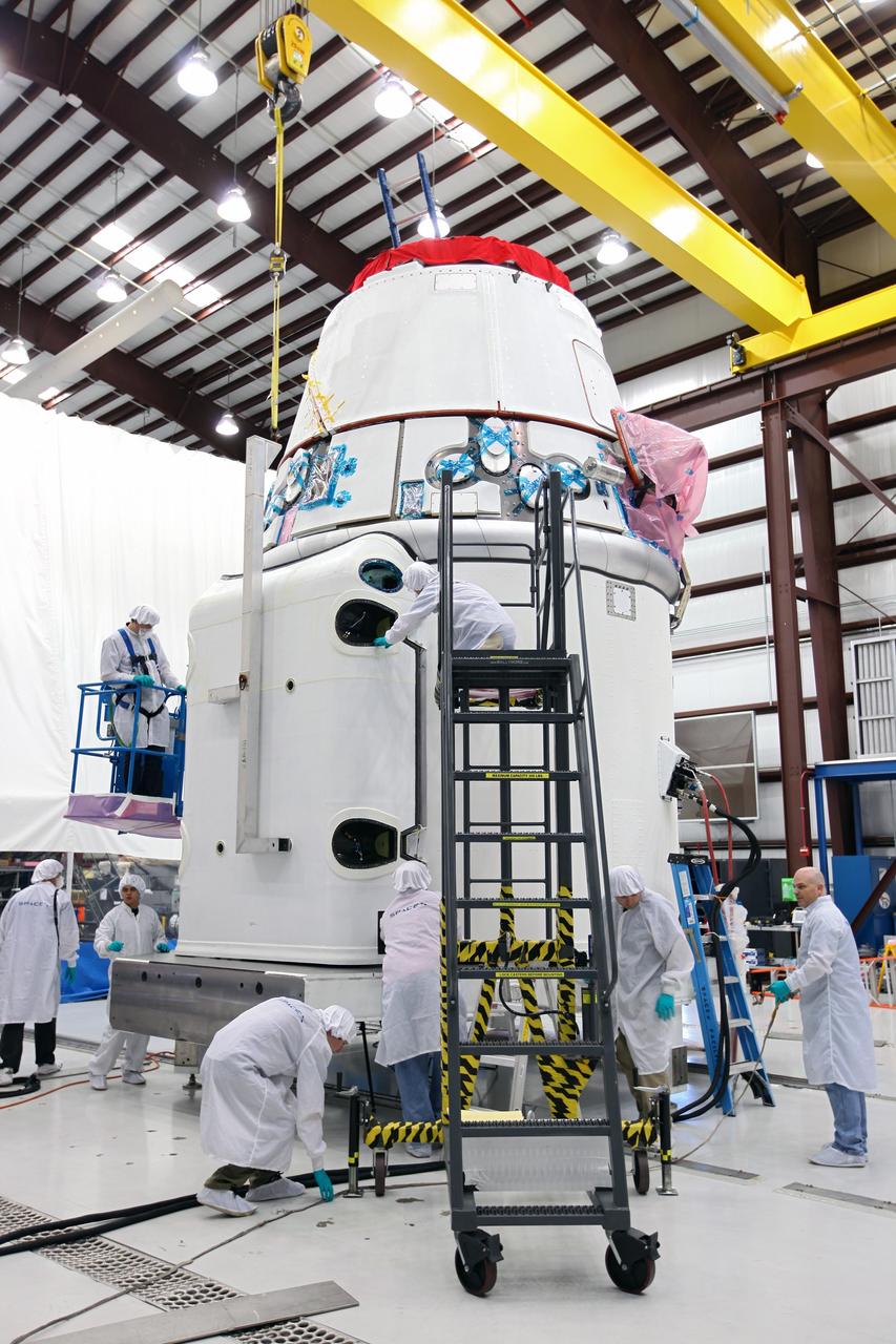 CAPE CANAVERAL, Fla. – Workers guide a solar array fairing into place inside the processing hangar used by Space Exploration Technologies, or SpaceX, at Cape Canaveral Air Force Station, Fla. The fairing will be installed on the Dragon spacecraft undergoing launch preparations inside the hangar. The spacecraft will launch on the upcoming SpaceX CRS-2 mission. The flight will be the second commercial resupply mission to the International Space Station by SpaceX. NASA has contracted for a total of 12 commercial resupply flights from SpaceX and eight from the Orbital Sciences Corp. Photo credit: NASA/Kim Shiflett