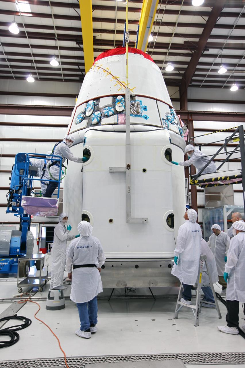 CAPE CANAVERAL, Fla. – Workers guide a solar array fairing into place inside the processing hangar used by Space Exploration Technologies, or SpaceX, at Cape Canaveral Air Force Station, Fla. The fairing will be installed on the Dragon spacecraft undergoing launch preparations inside the hangar. The spacecraft will launch on the upcoming SpaceX CRS-2 mission. The flight will be the second commercial resupply mission to the International Space Station by SpaceX. NASA has contracted for a total of 12 commercial resupply flights from SpaceX and eight from the Orbital Sciences Corp. Photo credit: NASA/Kim Shiflett