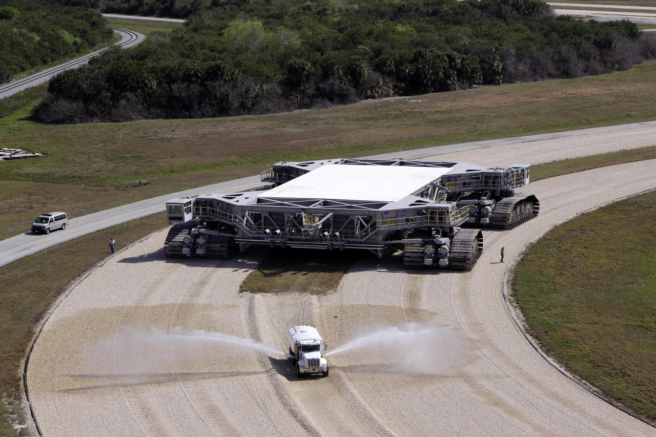 CAPE CANAVERAL, Fla. – At NASA’s Kennedy Space Center in Florida, the crawler-transporter 2, or CT-2, is on its way from the Vehicle Assembly Building to the Park Site west of the building. The transporter has new brakes and mufflers and a recently-painted white roof deck. Out in front is a truck spraying water to control the dust on the crawlerway. The Ground Systems Development and Operations Program office at Kennedy is overseeing the upgrades to CT-2 so that it can carry NASA’s Space Launch System heavy-lift rocket, which is under design, and new Orion spacecraft to the launch pad. The crawler-transporters were used to carry the mobile launcher platform and space shuttle to Launch Complex 39 for space shuttle launches for 30 years. Photo credit: NASA/Jim Grossmann