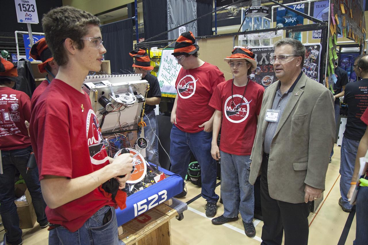 ORLANDO, Fla. – Ed Mango, program manager of NASA's Commercial Crew Program, discusses technological advances with teams of high school students taking part in the FIRST Robotics Competition's 2013 Orlando Regional in the University of Central Florida Arena. The student-built robots were required to throw discs into boxes or make climbs to score points. Photo credit: NASA/Frankie Martin