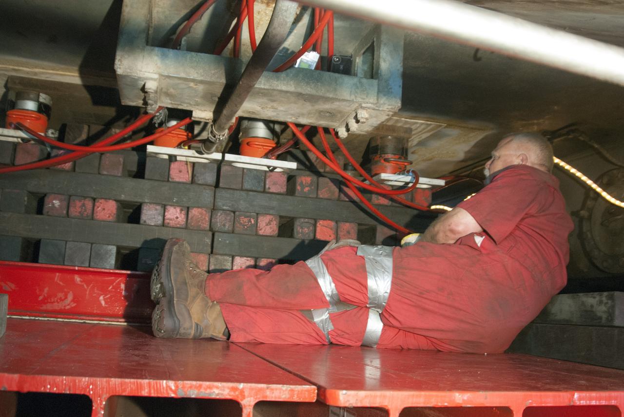 CAPE CANAVERAL, Fla. -- In the Vehicle Assembly Building at NASA’s Kennedy Space Center in Florida, a technician positions a jack to lift crawler-transporter 2, or CT-2, four feet off the floor to facilitate removal of the roller bearing assemblies. After inspections, new assemblies will be installed.      The Ground Systems Development and Operations Program office at Kennedy is overseeing the upgrades to CT-2 so that it can carry NASA’s Space Launch System heavy-lift rocket and new Orion spacecraft to the launch pad. For more than 45 years the crawler-transporters were used to transport the mobile launcher platform and the Apollo-Saturn V rockets and, later, space shuttles to Launch Pads 39A and B. Photo credit: NASA/Charisse Nahser