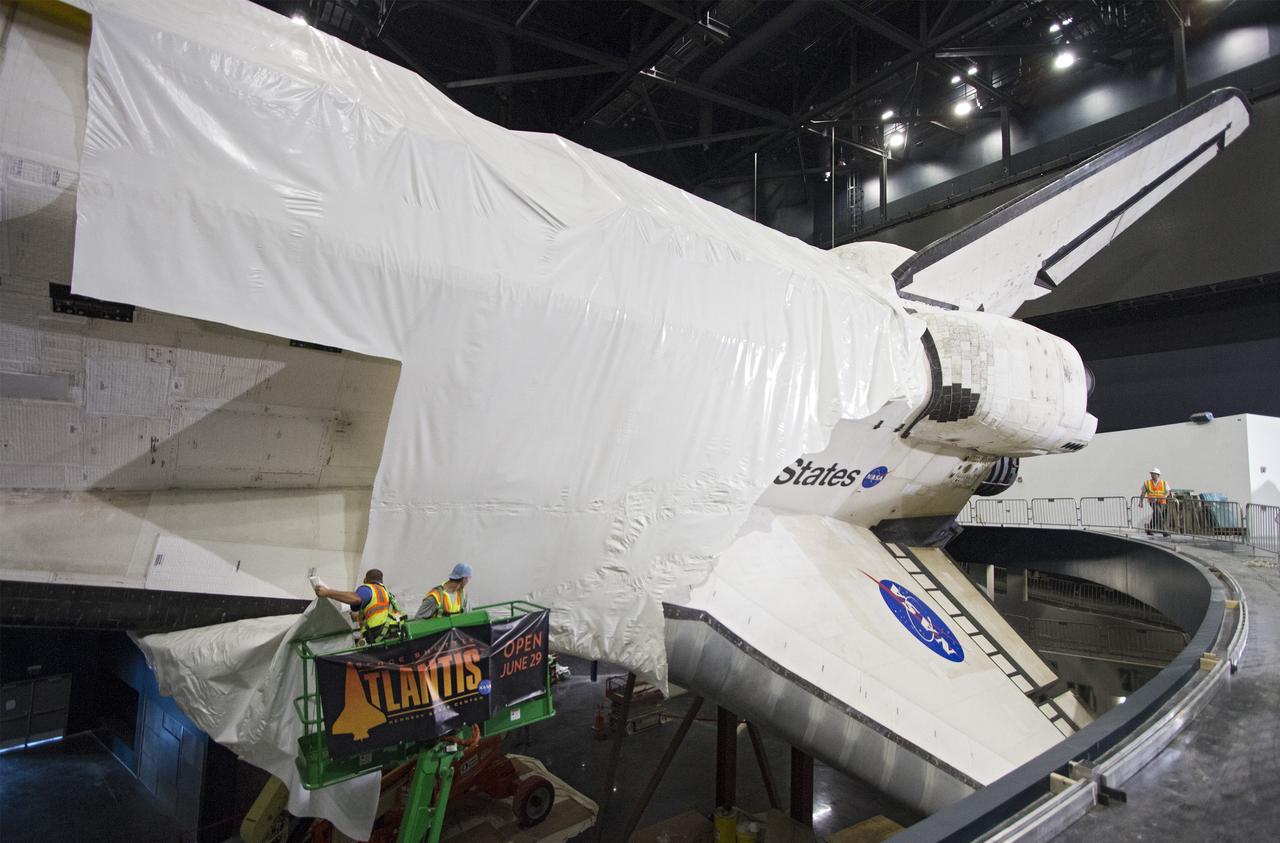 CAPE CANAVERAL, Fla. -- At the Kennedy Space Center Visitor Complex in Florida, construction crews are removing 16,000 square feet of plastic shrink-wrap from the space shuttle Atlantis. The spacecraft was enclosed in the plastic shrink-wrap since November of last year to protect the artifact from dust and debris during construction of the 90,000-square-foot facility.      Last November, the space shuttle Atlantis made its historic final journey to its new home, traveling 10 miles from the Kennedy Space Center's Vehicle Assembly Building to the spaceport's visitor complex. The new $100 million "Space Shuttle Atlantis" facility will include interactive exhibits that tell the story of the 30-year Space Shuttle Program and highlights the future of space exploration. The "Space Shuttle Atlantis" exhibit scheduled to open June 29, 2013.Photo credit: NASA/Cory Huston