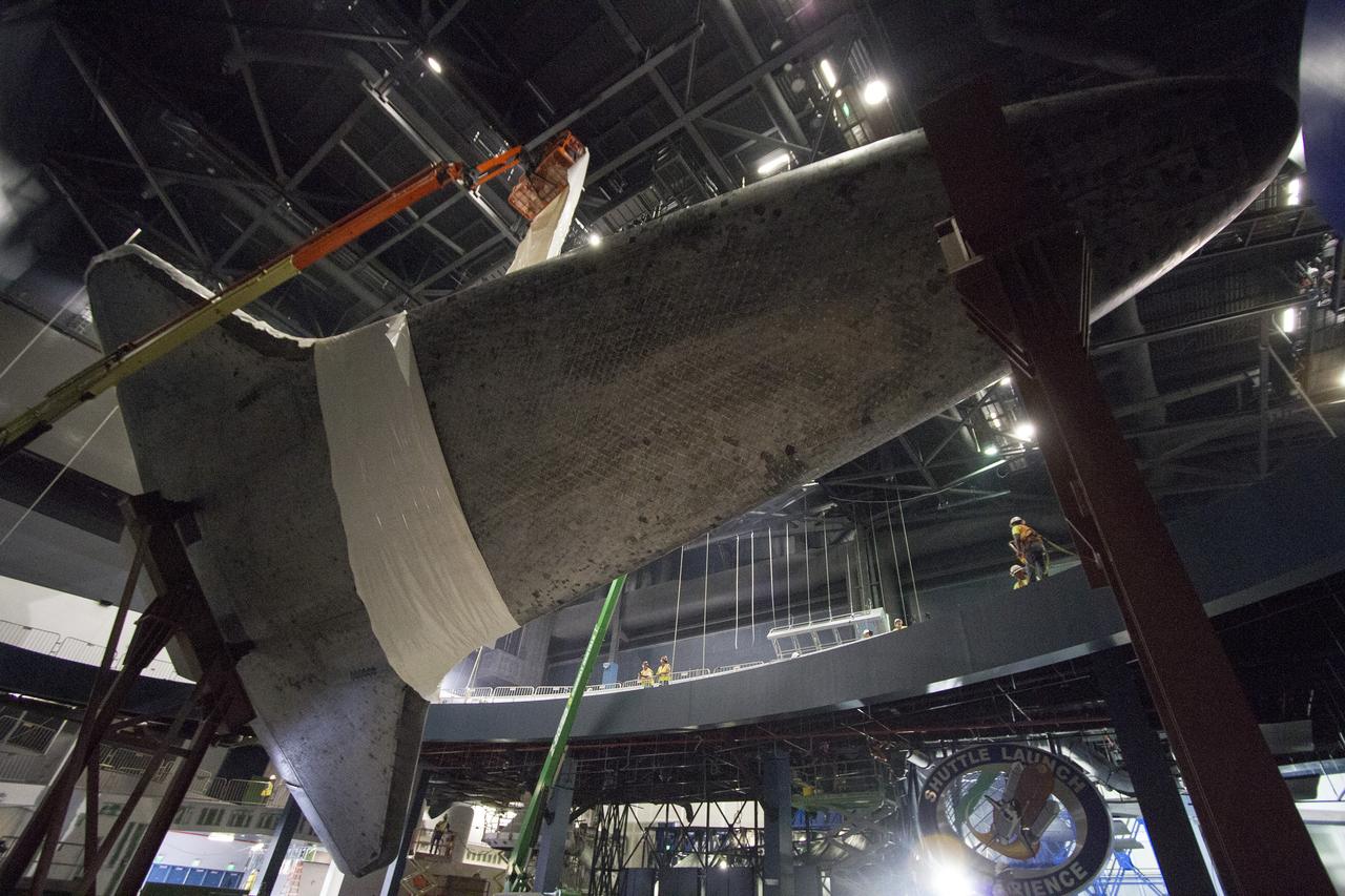 CAPE CANAVERAL, Fla. -- At the Kennedy Space Center Visitor Complex in Florida, construction crews are removing 16,000 square feet of plastic shrink-wrap from the space shuttle Atlantis. The spacecraft was enclosed in the plastic shrink-wrap since November of last year to protect the artifact from dust and debris during construction of the 90,000-square-foot facility. Last November, the space shuttle Atlantis made its historic final journey to its new home, traveling 10 miles from the Kennedy Space Center's Vehicle Assembly Building to the spaceport's visitor complex. The new $100 million "Space Shuttle Atlantis" facility will include interactive exhibits that tell the story of the 30-year Space Shuttle Program and highlights the future of space exploration. The "Space Shuttle Atlantis" exhibit scheduled to open June 29, 2013.Photo credit: NASA/Cory Huston