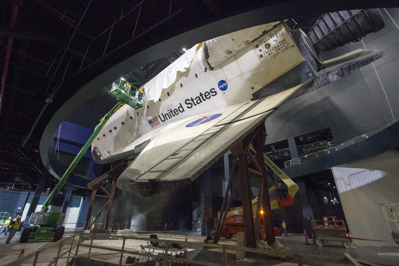 CAPE CANAVERAL, Fla. -- At the Kennedy Space Center Visitor Complex in Florida, construction crews are removing 16,000 square feet of plastic shrink-wrap from the space shuttle Atlantis. The spacecraft was enclosed in the plastic shrink-wrap since November of last year to protect the artifact from dust and debris during construction of the 90,000-square-foot facility. Last November, the space shuttle Atlantis made its historic final journey to its new home, traveling 10 miles from the Kennedy Space Center's Vehicle Assembly Building to the spaceport's visitor complex. The new $100 million "Space Shuttle Atlantis" facility will include interactive exhibits that tell the story of the 30-year Space Shuttle Program and highlights the future of space exploration. The "Space Shuttle Atlantis" exhibit scheduled to open June 29, 2013.Photo credit: NASA/Cory Huston
