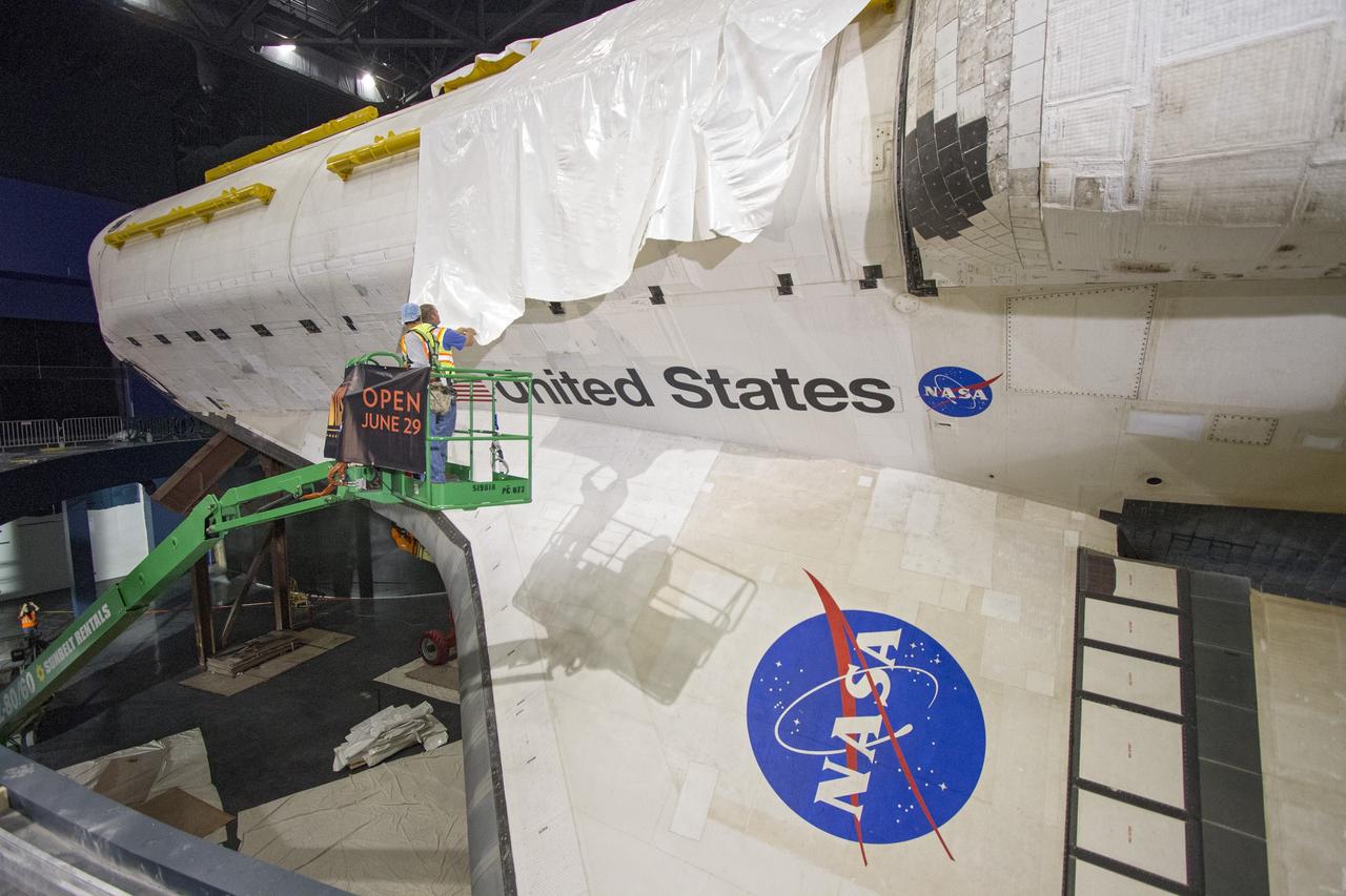 CAPE CANAVERAL, Fla. -- At the Kennedy Space Center Visitor Complex in Florida, construction crews are removing 16,000 square feet of plastic shrink-wrap from the space shuttle Atlantis. The spacecraft was enclosed in the plastic shrink-wrap since November of last year to protect the artifact from dust and debris during construction of the 90,000-square-foot facility. Last November, the space shuttle Atlantis made its historic final journey to its new home, traveling 10 miles from the Kennedy Space Center's Vehicle Assembly Building to the spaceport's visitor complex. The new $100 million "Space Shuttle Atlantis" facility will include interactive exhibits that tell the story of the 30-year Space Shuttle Program and highlights the future of space exploration. The "Space Shuttle Atlantis" exhibit scheduled to open June 29, 2013.Photo credit: NASA/Cory Huston