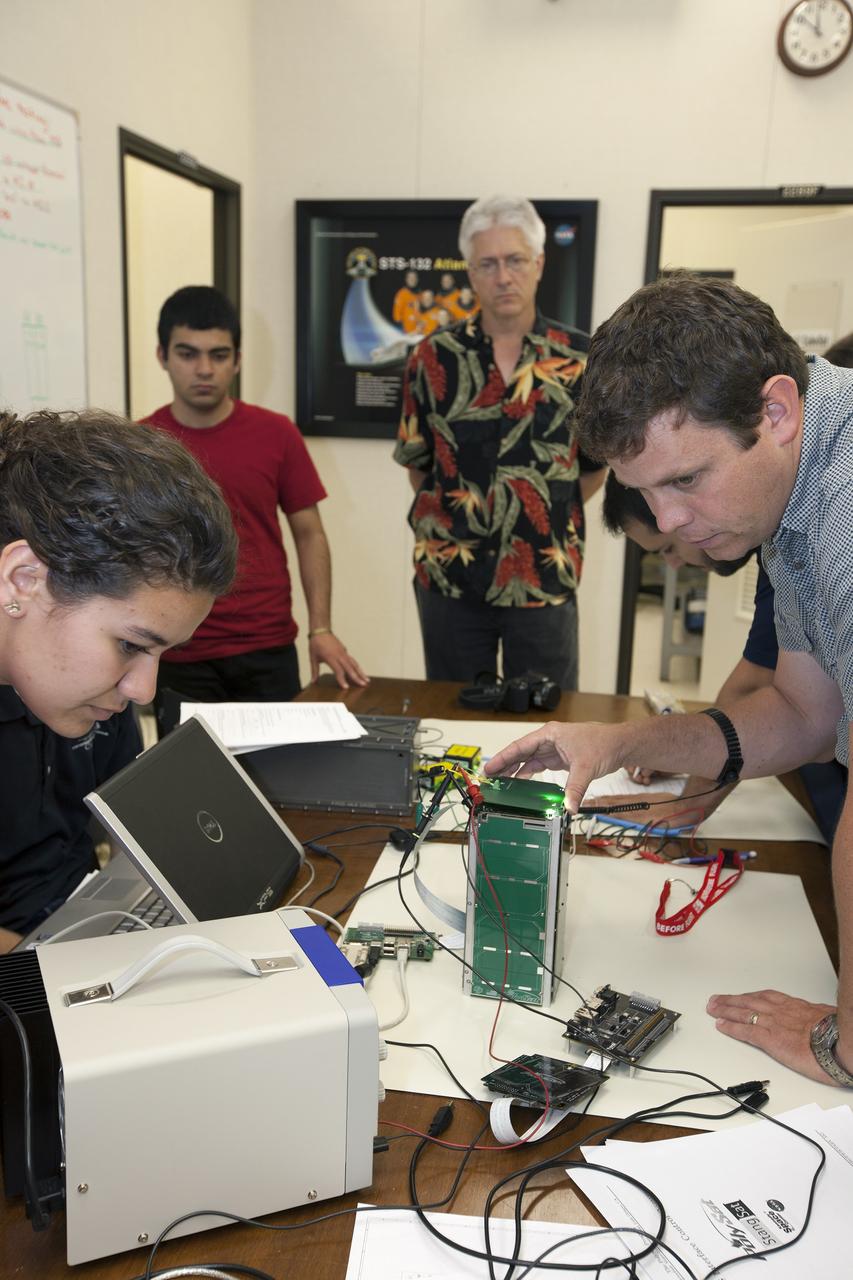 CAPE CANAVERAL, Fla. – Students from California Polytechnic Institute, or CalPoly, and Merritt Island High School in Florida perform integration tests on a pair of cubesats they will fly on a suborbital mission in the summer. A team from each school built a satellite and the two will work together inside a small rocket to measure vibration and other data during launch. NASA engineers, including Shaun Daly, in gray shirt, are acting as mentors for the project and some of the space agency's labs at Kennedy Space Center, including this one inside the Operations and Checkout Building, are being used by the teams. Photo credit: NASA/Kim Shiflett