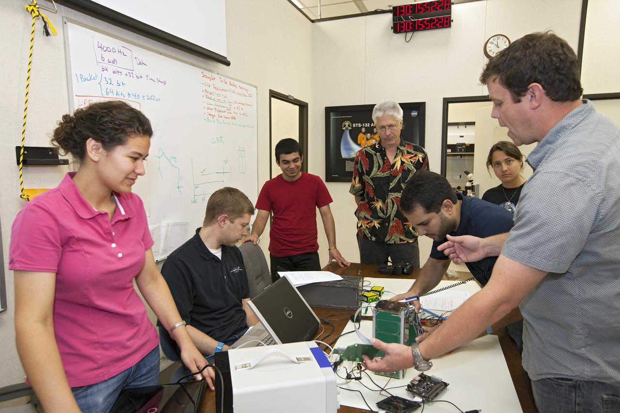 CAPE CANAVERAL, Fla. – Students from California Polytechnic Institute, or CalPoly, and Merritt Island High School in Florida perform integration tests on a pair of cubesats they will fly on a suborbital mission in the summer. A team from each school built a satellite and the two will work together inside a small rocket to measure vibration and other data during launch. NASA engineers, including Shaun Daly, in gray shirt, are acting as mentors for the project and some of the space agency's labs at Kennedy Space Center, including this one inside the Operations and Checkout Building, are being used by the teams. Photo credit: NASA/Kim Shiflett