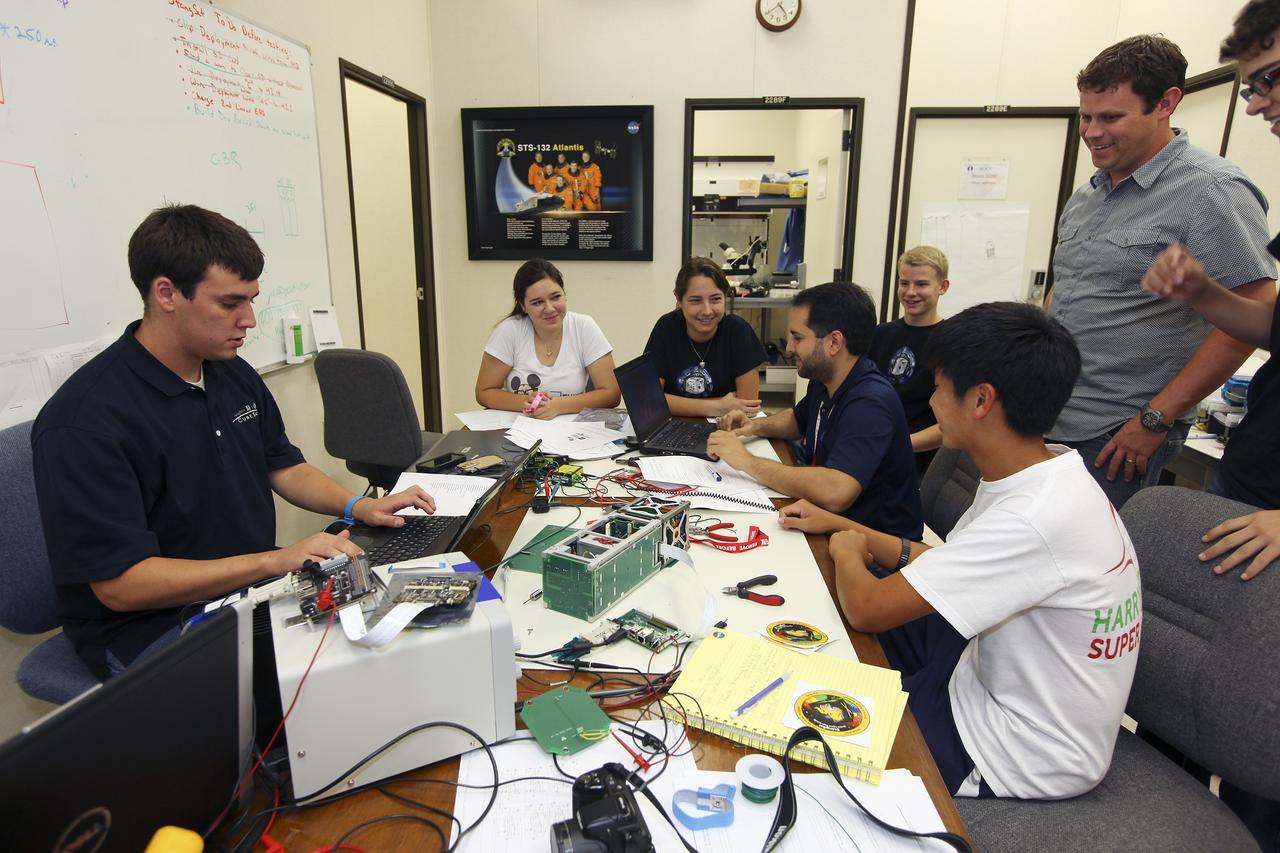 CAPE CANAVERAL, Fla. – Students from California Polytechnic Institute, or CalPoly, and Merritt Island High School in Florida perform integration tests on a pair of cubesats they will fly on a suborbital mission in the summer. A team from each school built a satellite and the two will work together inside a small rocket to measure vibration and other data during launch. NASA engineers, including Shaun Daly, in gray shirt, are acting as mentors for the project and some of the space agency's labs at Kennedy Space Center, including this one inside the Operations and Checkout Building, are being used by the teams. Photo credit: NASA/Kim Shiflett