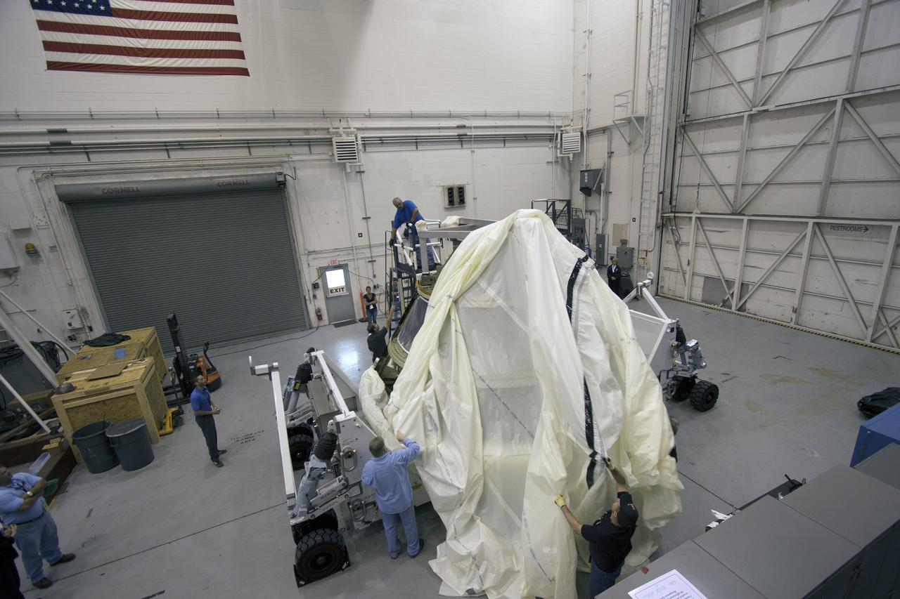 CAPE CANAVERAL, Fla. -- At NASA’s Kennedy Space Center in Florida,  Lockheed Martin crews begin uncovering the Orion ground test vehicle in the Launch Equipment Test Facility, or LETF. The GTA was moved from the Operations and Checkout Facility to the LETF for a series of pyrotechnic bolt tests.  The GTA is being used for path finding operations in the O&C, including simulated manufacturing and assembly procedures.    Launching atop NASA's heavy-lift Space Launch System SLS, which also is under development, the Orion Multi-Purpose Crew Vehicle MPCV will serve as the exploration vehicle that will carry astronaut crews beyond low Earth orbit. It also will provide emergency abort capabilities, sustain the crew during space travel and provide safe re-entry from deep space return velocities. For more information, visit www.nasa.gov/orion. Photo credit: Jim Grossman