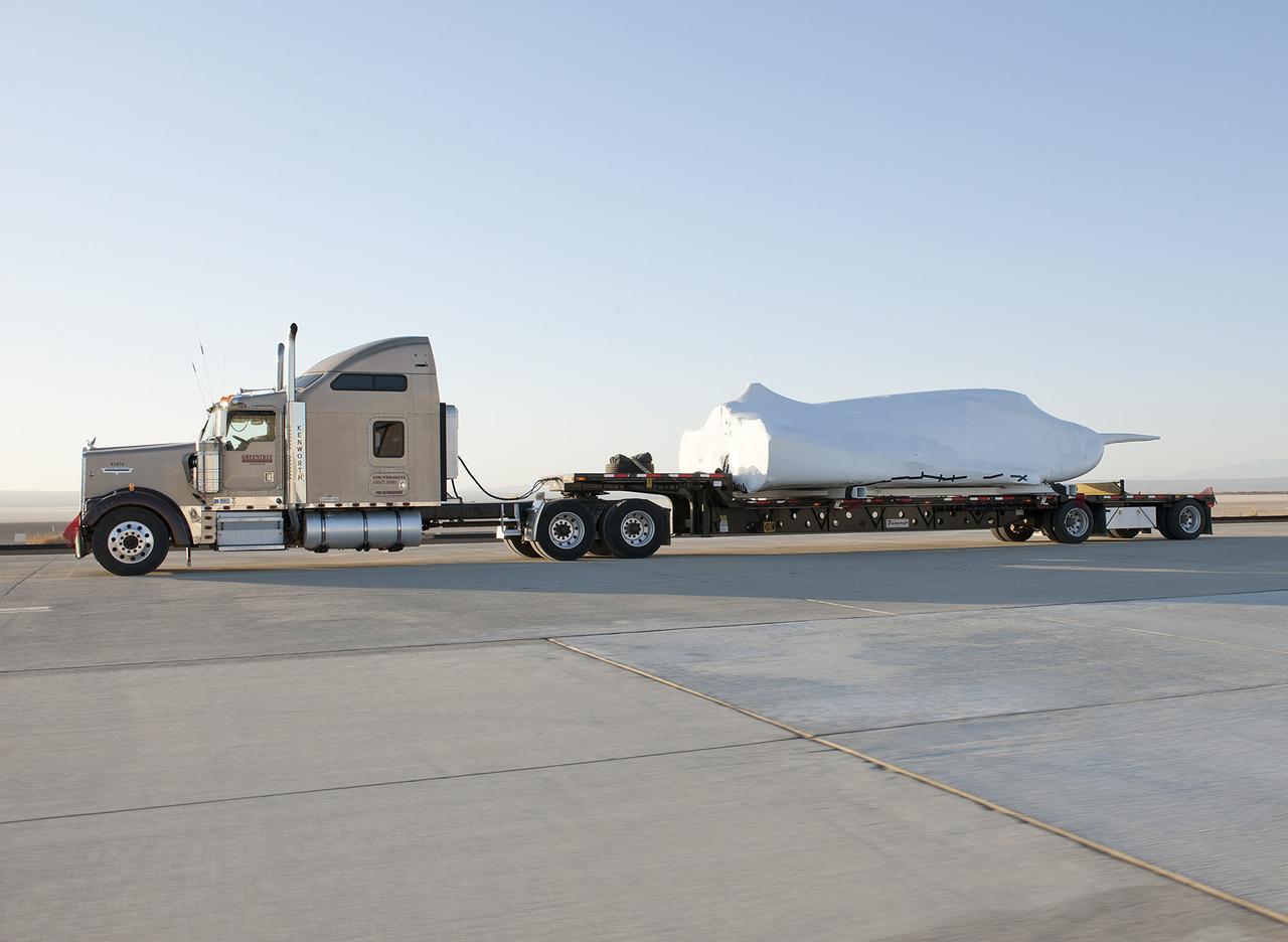 EDWARDS, Calif. – ED13-0142-11: The truck and trailer that transported the Dream Chaser engineering test article from Sierra Nevada Corporation, or SNC, Space Systems facility in Louisville, Colo., arrives on the aircraft ramp at NASA's Dryden Flight Research Center on Edwards Air Force Base, Calif., early in the morning. Based on NASA's HL-20 lifting body design, the Dream Chaser will begin its approach-and-landing flight test program in collaboration with NASA's Commercial Crew Program this summer.    SNC is one of three companies working with NASA's Commercial Crew Program, or CCP, during the agency's Commercial Crew Integrated Capability, or CCiCap, initiative, which is intended to lead to the availability of commercial human spaceflight services for government and commercial customers. To learn more about CCP and its industry partners, visit www.nasa.gov/commercialcrew. Image credit: NASA/Tom Tschida