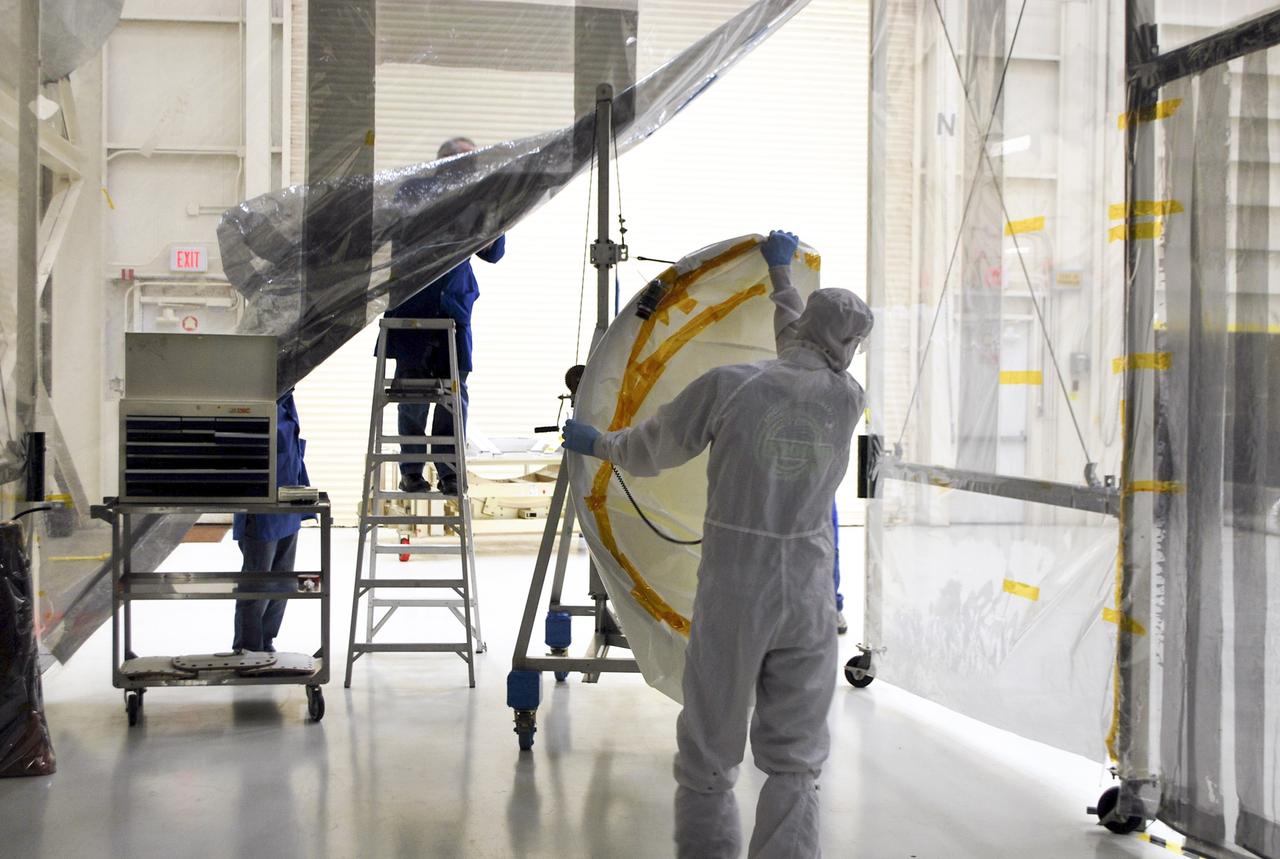 VANDENBERG AFB – Engineers move the port side of the payload fairing before it is connected into place for NASA's IRIS spacecraft. The fairing connects to the nose of the Orbital Sciences Pegasus XL rocket that will lift the solar observatory into orbit in June. The work is taking place in a hangar at Vandenberg Air Force Base where IRIS, short for Interface Region Imaging Spectrograph, is being prepared for launch on a Pegasus XL rocket. Scheduled for launch from Vandenberg June 26, IRIS will open a new window of discovery by tracing the flow of energy and plasma through the chromospheres and transition region into the sun’s corona using spectrometry and imaging. IRIS fills a crucial gap in our ability to advance studies of the sun-to-Earth connection by tracing the flow of energy and plasma through the foundation of the corona and the region around the sun known as the heliosphere. Photo credit: NASA/Randy Beaudoin