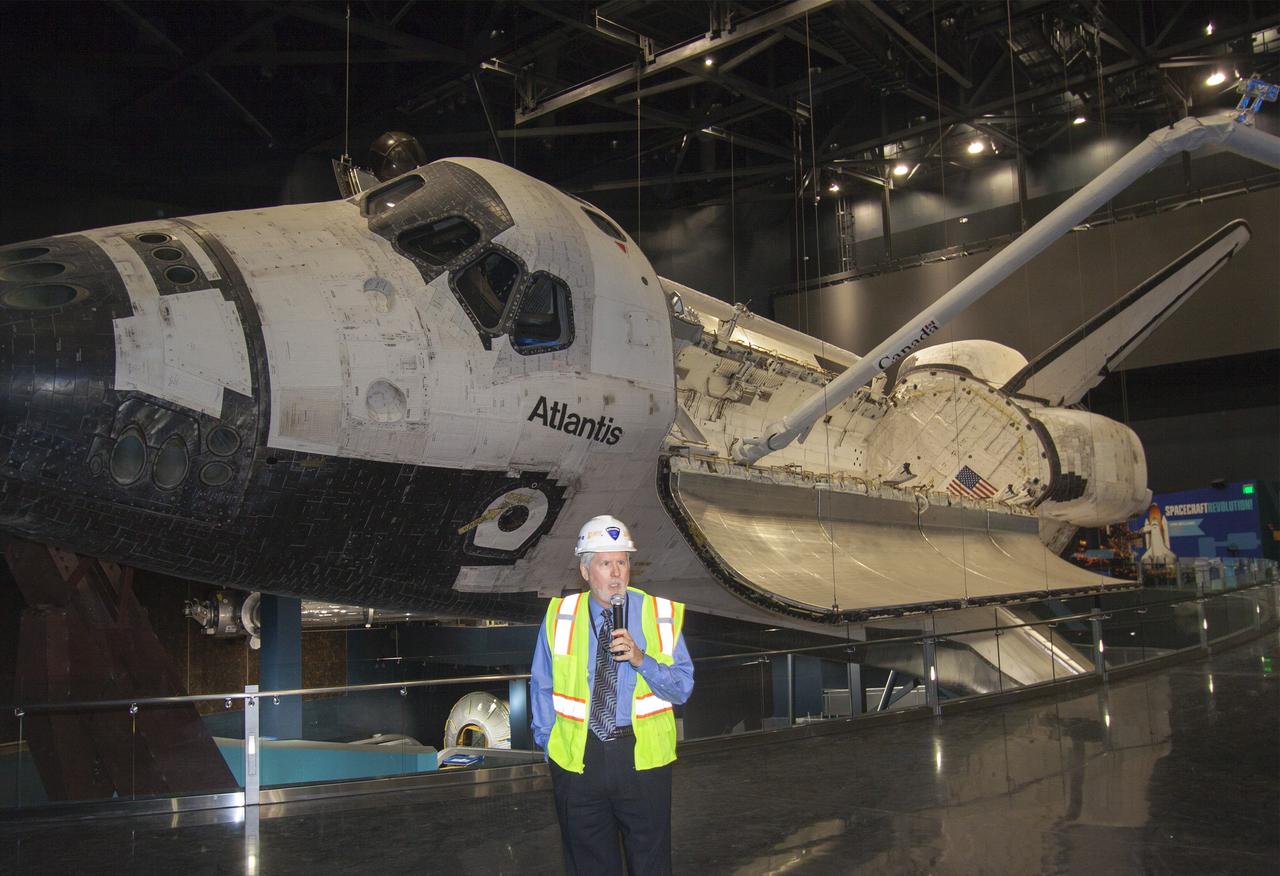 CAPE CANAVERAL, Fla. – At the Kennedy Space Center Visitor Complex in Florida, Bill Moore, chief operating officer with Delaware North Companies Parks & Resorts, speaks to members of the media during a tour of the new “Space Shuttle Atlantis” exhibit, a 90,000-square-foot facility, scheduled to open June 29, 2013. Behind Moore, space shuttle Atlantis’ payload bay doors are open and the orbiter has been tilted at a 43.21 angle to the portside and supported by special jacks to elevate it 26 feet from the ground. The robotic arm has been installed in the payload bay.    The new $100 million facility will include interactive exhibits that tell the story of the 30-year Space Shuttle Program and highlight the future of space exploration. Visitors to the exhibit will get an up close look at Atlantis with its payload bay doors open, similar to how it looked in space. Photo credit: NASA/Jim Grossmann