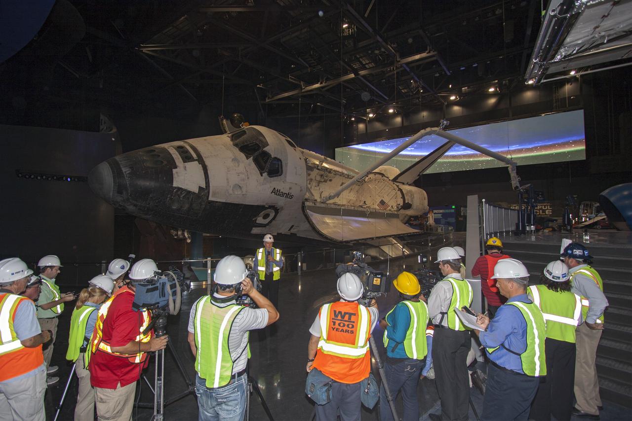 CAPE CANAVERAL, Fla. – At the Kennedy Space Center Visitor Complex in Florida, Bill Moore, chief operating officer with Delaware North Companies Parks & Resorts, speaks to members of the media during a tour of the new “Space Shuttle Atlantis” exhibit, a 90,000-square-foot facility, scheduled to open June 29, 2013. Behind Moore, space shuttle Atlantis’ payload bay doors are open and the orbiter has been tilted at a 43.21 angle to the portside and supported by special jacks to elevate it 26 feet from the ground. The robotic arm has been installed in the payload bay.    The new $100 million facility will include interactive exhibits that tell the story of the 30-year Space Shuttle Program and highlight the future of space exploration. Visitors to the exhibit will get an up close look at Atlantis with its payload bay doors open, similar to how it looked in space. Photo credit: NASA/Jim Grossmann
