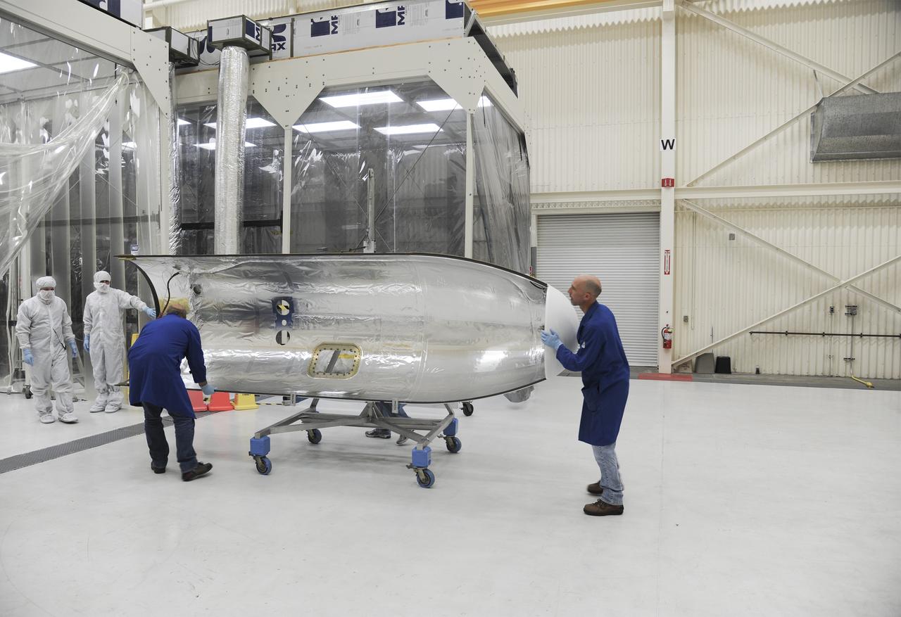 VANDENBERG AFB – Orbital Sciences team members move the second half of the payload fairing before it is placed over NASA's IRIS spacecraft. The fairing connects to the nose of the Orbital Sciences Pegasus XL rocket that will lift the solar observatory into orbit in June. The work is taking place in a hangar at Vandenberg Air Force Base where IRIS, short for Interface Region Imaging Spectrograph, is being prepared for launch on a Pegasus XL rocket. Scheduled for launch from Vandenberg June 26, IRIS will open a new window of discovery by tracing the flow of energy and plasma through the chromospheres and transition region into the sun’s corona using spectrometry and imaging. IRIS fills a crucial gap in our ability to advance studies of the sun-to-Earth connection by tracing the flow of energy and plasma through the foundation of the corona and the region around the sun known as the heliosphere. Photo credit: NASA/Tony Vauclin