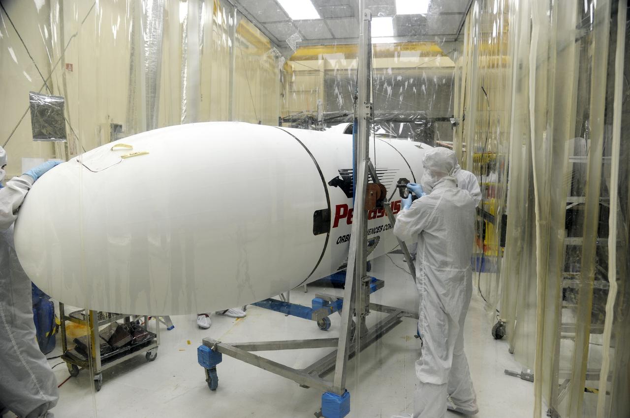 VANDENBERG AFB – Orbital Sciences team members move the second half of the payload fairing before it is placed over NASA's IRIS spacecraft. The fairing connects to the nose of the Orbital Sciences Pegasus XL rocket that will lift the solar observatory into orbit in June. The work is taking place in a hangar at Vandenberg Air Force Base where IRIS, short for Interface Region Imaging Spectrograph, is being prepared for launch on a Pegasus XL rocket. Scheduled for launch from Vandenberg June 26, IRIS will open a new window of discovery by tracing the flow of energy and plasma through the chromospheres and transition region into the sun’s corona using spectrometry and imaging. IRIS fills a crucial gap in our ability to advance studies of the sun-to-Earth connection by tracing the flow of energy and plasma through the foundation of the corona and the region around the sun known as the heliosphere. Photo credit: NASA/Tony Vauclin