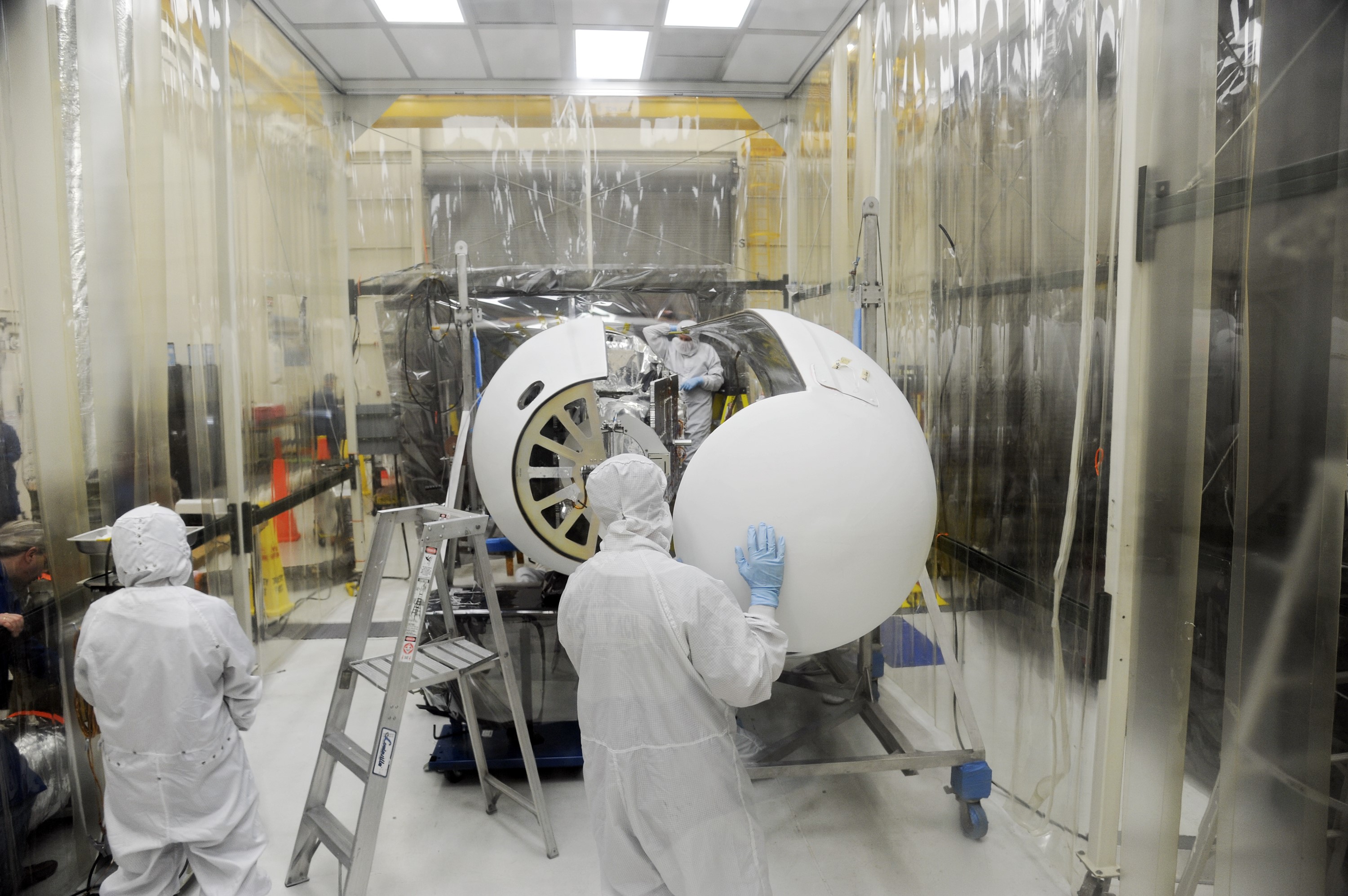 VANDENBERG AFB – Orbital Sciences team members move the second half of the payload fairing before it is placed over NASA's IRIS spacecraft. The fairing connects to the nose of the Orbital Sciences Pegasus XL rocket that will lift the solar observatory into orbit in June. The work is taking place in a hangar at Vandenberg Air Force Base where IRIS, short for Interface Region Imaging Spectrograph, is being prepared for launch on a Pegasus XL rocket. Scheduled for launch from Vandenberg June 26, IRIS will open a new window of discovery by tracing the flow of energy and plasma through the chromospheres and transition region into the sun’s corona using spectrometry and imaging. IRIS fills a crucial gap in our ability to advance studies of the sun-to-Earth connection by tracing the flow of energy and plasma through the foundation of the corona and the region around the sun known as the heliosphere. Photo credit: NASA/Tony Vauclin