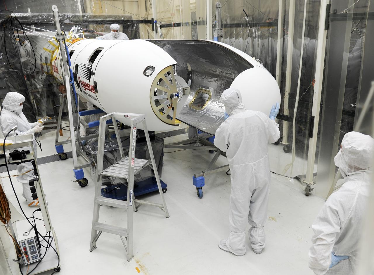 VANDENBERG AFB – Orbital Sciences team members move the second half of the payload fairing before it is placed over NASA's IRIS spacecraft. The fairing connects to the nose of the Orbital Sciences Pegasus XL rocket that will lift the solar observatory into orbit in June. The work is taking place in a hangar at Vandenberg Air Force Base where IRIS, short for Interface Region Imaging Spectrograph, is being prepared for launch on a Pegasus XL rocket. Scheduled for launch from Vandenberg June 26, IRIS will open a new window of discovery by tracing the flow of energy and plasma through the chromospheres and transition region into the sun’s corona using spectrometry and imaging. IRIS fills a crucial gap in our ability to advance studies of the sun-to-Earth connection by tracing the flow of energy and plasma through the foundation of the corona and the region around the sun known as the heliosphere. Photo credit: NASA/Tony Vauclin