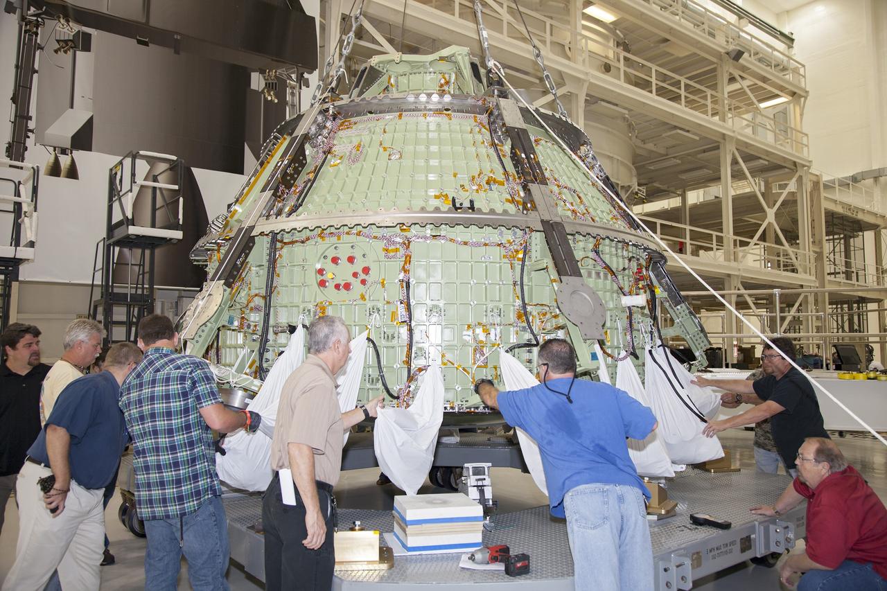 CAPE CANAVERAL, Fla. – Inside the Operations and Checkout Building high bay at NASA’s Kennedy Space Center in Florida, technicians help secure the Orion crew module onto a work stand after a crane was used to lift it out of a special test. Lockheed Martin Space Systems and NASA engineers performed a series of static load tests on Orion that simulated the massive loads the spacecraft would experience during its mission.    Orion is the exploration spacecraft designed to carry crews to space beyond low Earth orbit. It will provide emergency abort capability, sustain the crew during the space travel and provide safe re-entry from deep space return velocities. Orion’s first unpiloted test flight, Exploration Flight Test 1, is scheduled to launch in 2014 atop a Delta IV rocket. A second uncrewed flight test is scheduled for 2017 on NASA’s Space Launch System rocket. For more information, visit http://www.nasa.gov/orion. Photo credit: NASA/Daniel Casper