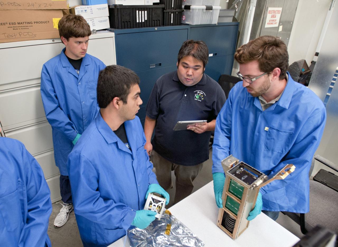 KSC-2013-2721 – SAN LUIS OBISPO, Calif. –Roland Coelho, third from left, CalPoly program lead, and members of the student launch team load a payload into a Poly Picosatellite Orbital Dispensor, or P-Pod nanolauncher/carrier in the CubeSat lab facility at California Polytechnic Institute, or CalPoly. The payload, which includes sensors and equipment carefully packaged into 4-inch cube sections, will ride in the body of a Garvey Spacecraft Corporation's Prospector P-18D rocket during a June 15 launch on a high-altitude, suborbital flight. Known as a CubeSat, the satellite will record shock, vibrations and heat inside the rocket. It will not be released during the test flight, but the results will be used to prove or strengthen their designs before they are carried into orbit in 2014 on a much larger rocket. Also, a new launcher/carrier of a lightweight design also is being tested for use on future missions to deploy the small spacecraft. The flight also is being watched closely as a model for trying out new or off-the-shelf technologies quickly before putting them in the pipeline for use on NASA's largest launchers. Built by several different organizations, including a university, a NASA field center and a high school, the spacecraft are four-inch cubes designed to fly on their own eventually, but will remain firmly attached to the rocket during the upcoming mission. For more information, visit http://www.nasa.gov/mission_pages/smallsats/elana/cubesatlaunchpreview.html Photo credit: VAFB/Kathi Peoples
