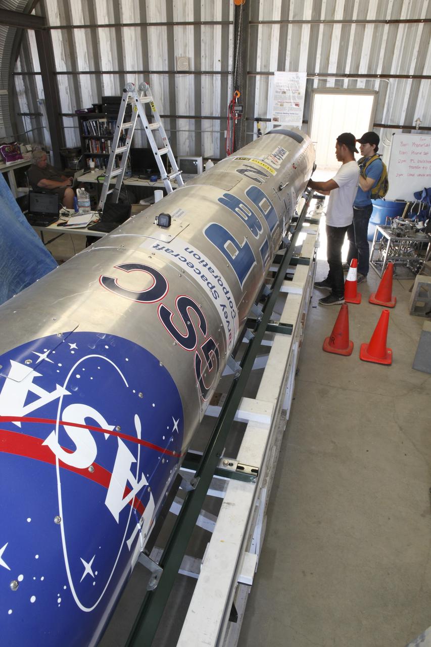 MOJAVE DESERT, Calif. – In the Mojave Desert in California, students and engineers pack the parachute in the Garvey Spacecraft Corporation's Prospector P-18D rocket. The work is in preparation for the June 15 launch of a on a high-altitude, suborbital flight. The rocket will carry four satellites made from four-inch cube section. Collectively known as CubeSats, the satellites will record shock, vibrations and heat inside the rocket. They will not be released during the test flight, but the results will be used to prove or strengthen their designs before they are carried into orbit in 2014 on a much larger rocket. A new, lightweight carrier is also being tested for use on future missions to deploy the small spacecraft. The flight also is being watched closely as a model for trying out new or off-the-shelf technologies quickly before putting them in the pipeline for use on NASA's largest launchers. Built by several different organizations, including a university, a NASA field center and a high school, the spacecraft are four-inch cubes designed to fly on their own eventually, but will remain firmly attached to the rocket during the upcoming mission. For more information, visit http://www.nasa.gov/mission_pages/smallsats/elana/cubesatlaunchpreview.html Photo credit: NASA/Dimitri Gerondidakis