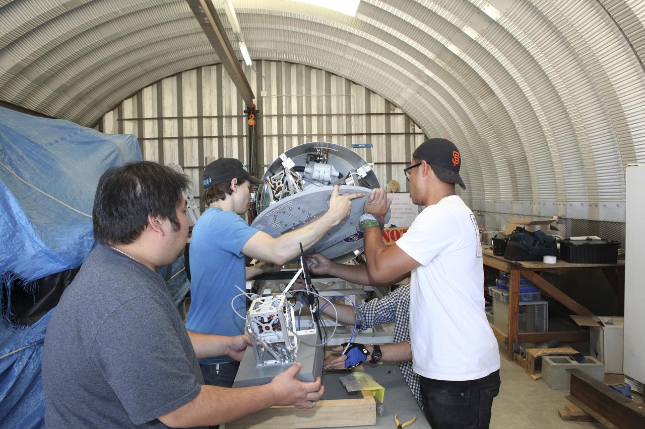 In the Mojave Desert in California, students and engineers checkout the Garvey Spacecraft Corporation's Prospector P-18D rocket engine. The rocket is scheduled for launch June 15 with the RUBICS-1 payload on a high-altitude, suborbital flight. The rocket will carry four satellites made from four-inch cube section.      Collectively known as CubeSats, the satellites will record shock, vibrations and heat inside the rocket. They will not be released during the test flight, but the results will be used to prove or strengthen their designs before they are carried into orbit in 2014 on a much larger rocket. A new, lightweight carrier is also being tested for use on future missions to deploy the small spacecraft. The flight also is being watched closely as a model for trying out new or off-the-shelf technologies quickly before putting them in the pipeline for use on NASA's largest launchers.  Built by several different organizations, including a university, a NASA field center and a high school, the spacecraft are four-inch cubes designed to fly on their own eventually, but will remain firmly attached to the rocket during the upcoming mission. For more information, visit http://www.nasa.gov/mission_pages/smallsats/elana/cubesatlaunchpreview.html Photo credit: NASA/Dimitri Gerondidakis