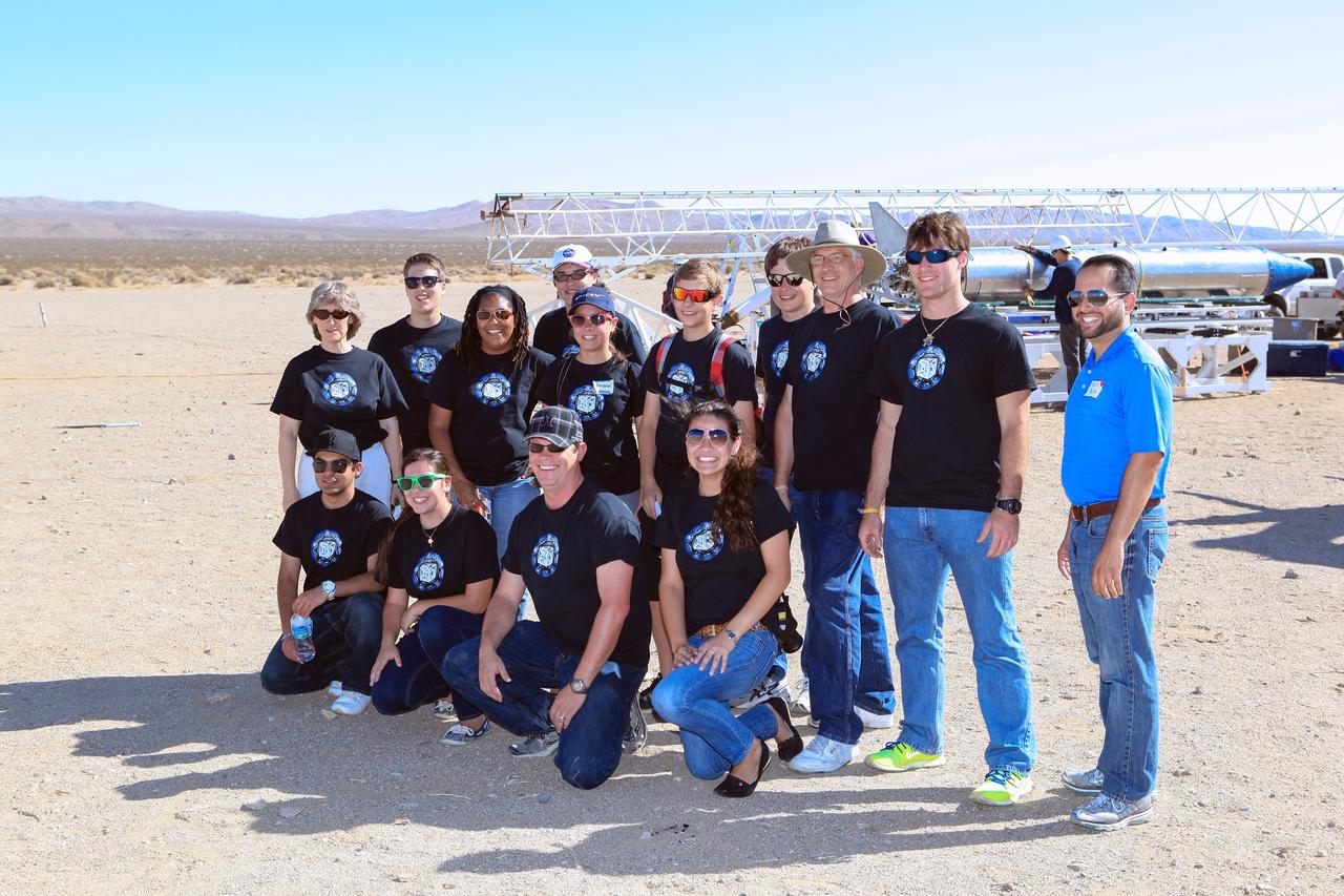MOJAVE DESERT, Calif. – In the Mojave Desert in California, a student StangSat Team of students from Merritt Island High School in Florida posed for a pre-launch photograph as the Garvey Spacecraft Corporation's Prospector P-18D rocket, in the background, was being prepared for flight at the Friends of Amateur Rocketry launch site. Kneeling from left to right, are: Gurkirat Kainth, Megan Mackool, NASA mentor Shaun Daly and Maurisa Orona. Standing from left to right, are: teacher sponsor Tracey Beatovich, Brian Robusto, NASA Education program manager Grace Johnson, Nathan Stephens, Briana Luthman, Jackson Kinney, Steven Krygier, NASA mentor Jim Kinney, Joshua Zirkle and NASA mentor Kelvin Ruiz. Collectively known as CubeSats, the satellites will record shock, vibrations and heat inside the rocket. They will not be released during the test flight, but the results will be used to prove or strengthen their designs before they are carried into orbit in 2014 on a much larger rocket. A new, lightweight carrier is also being tested for use on future missions to deploy the small spacecraft. The flight also is being watched closely as a model for trying out new or off-the-shelf technologies quickly before putting them in the pipeline for use on NASA's largest launchers. Built by several different organizations, including a university, a NASA field center and a high school, the spacecraft are four-inch cubes designed to fly on their own eventually, but will remain firmly attached to the rocket during the upcoming mission. For more information, visit http://www.nasa.gov/mission_pages/smallsats/elana/cubesatlaunchpreview.html Photo credit: NASA/Dimitri Gerondidakis